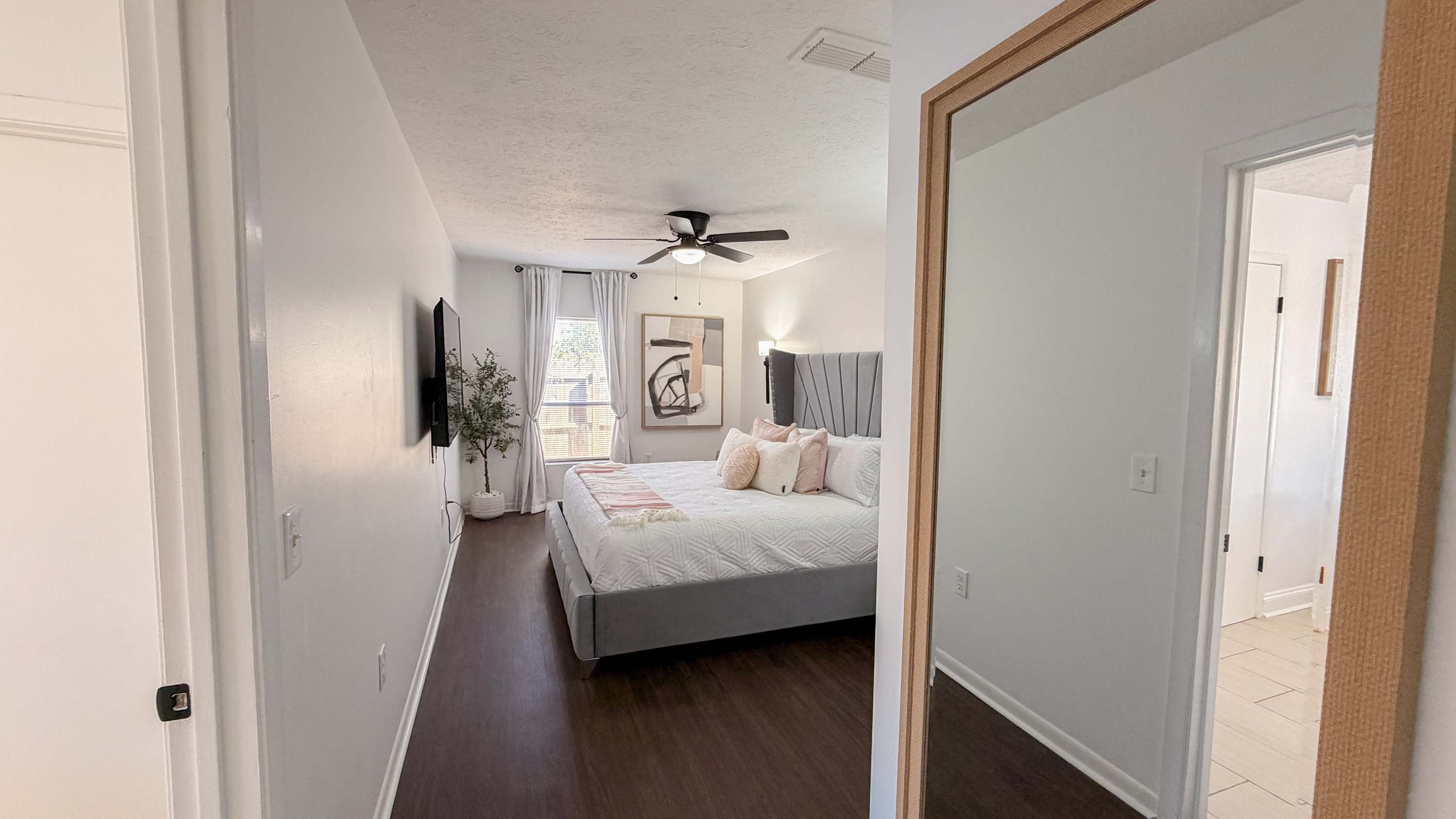 300 W 23rd Pl – Bright bedroom with a large bed, decorative pillows, wall artwork, and a window with curtains.