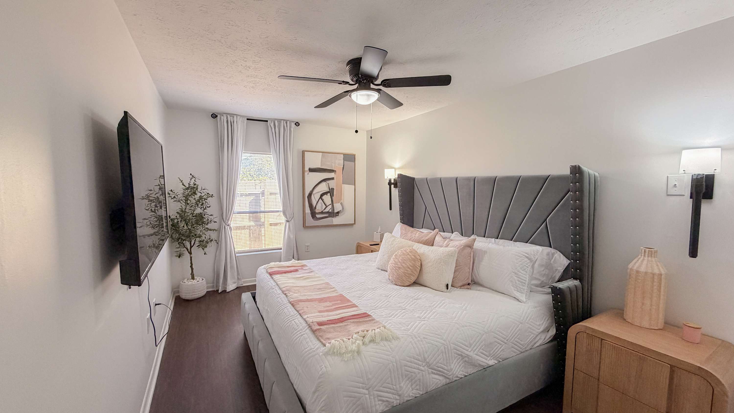 300 W 23rd Pl – Spacious bedroom with a large bed, TV, window, and decorative art.
