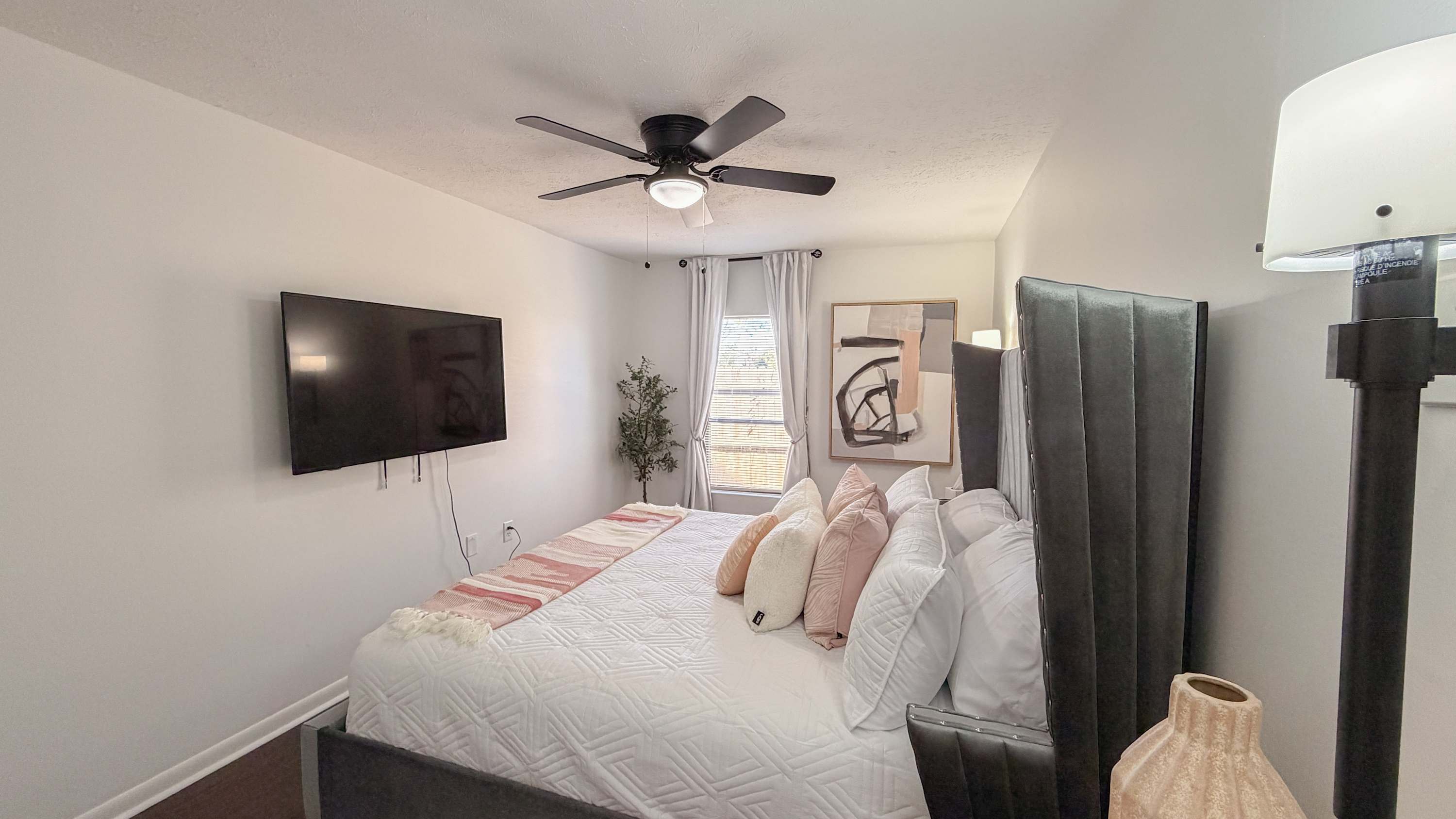 300 W 23rd Pl – Main bedroom with a king bed, large TV, window, and decorative plants.