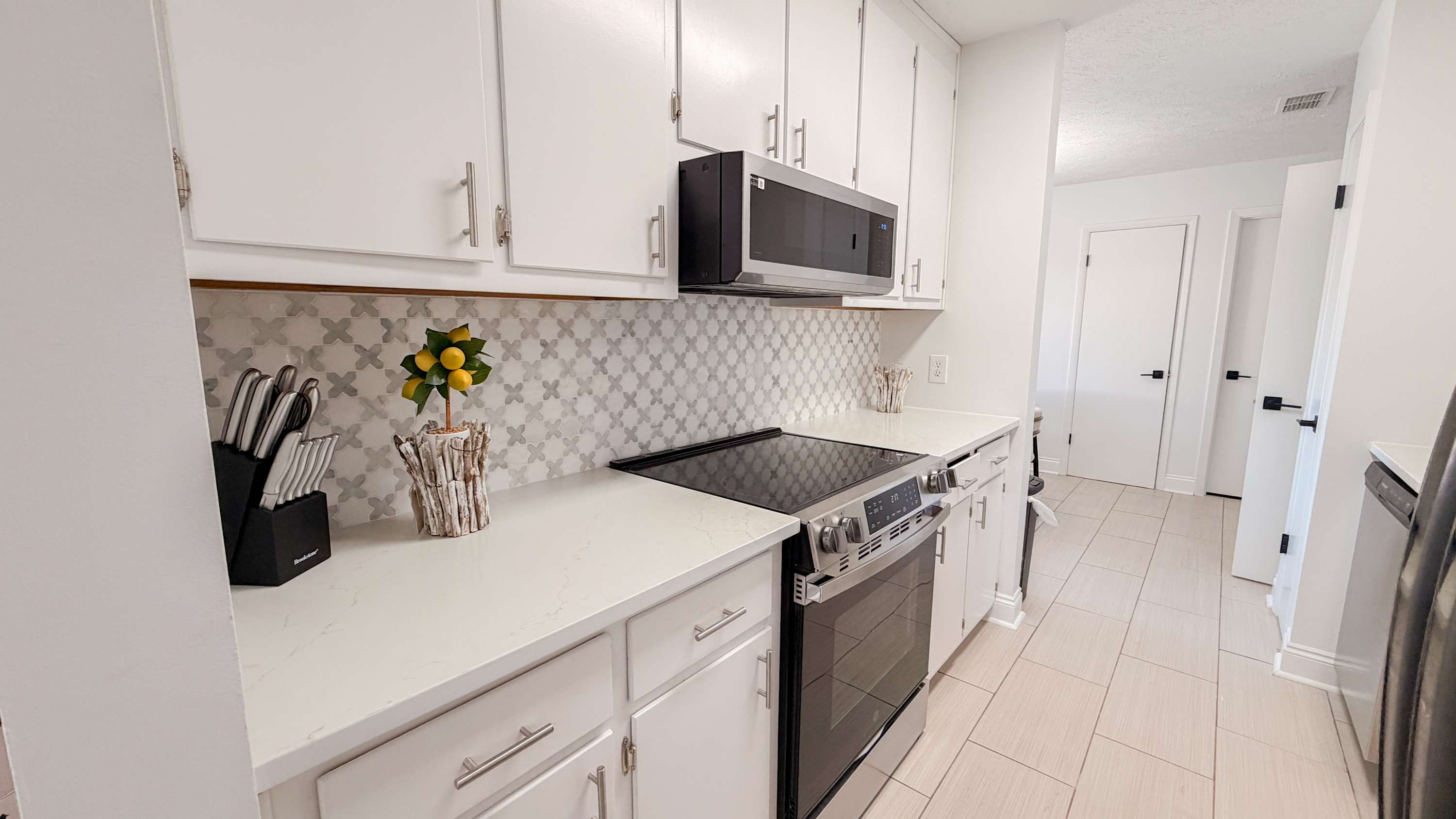 300 W 23rd Pl – Spacious kitchen with white cabinets, stainless steel appliances, and decorative backsplash.