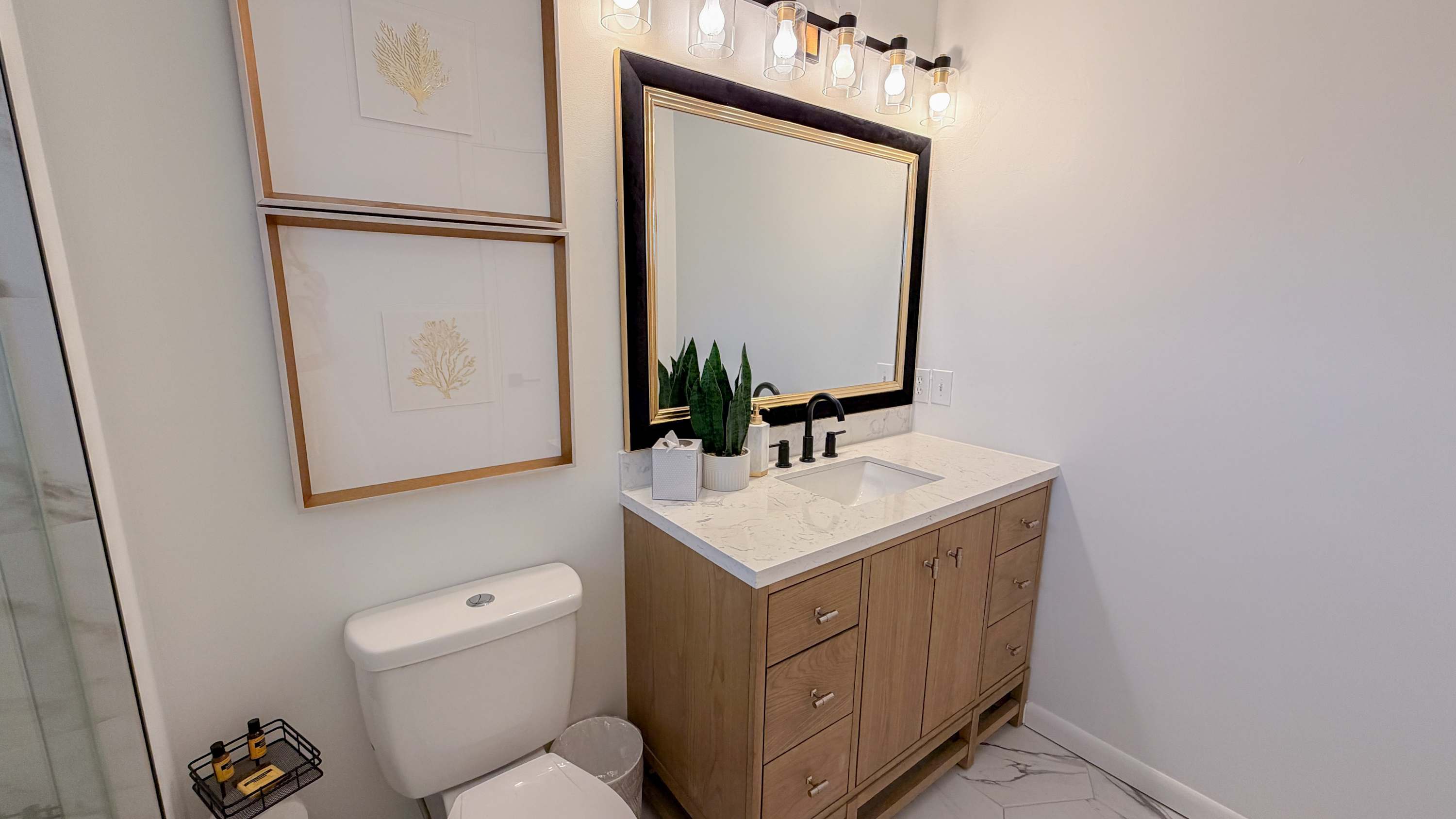 300 W 23rd Pl – Bathroom with wooden vanity, large mirror, sink, plants, and framed artwork on the wall.