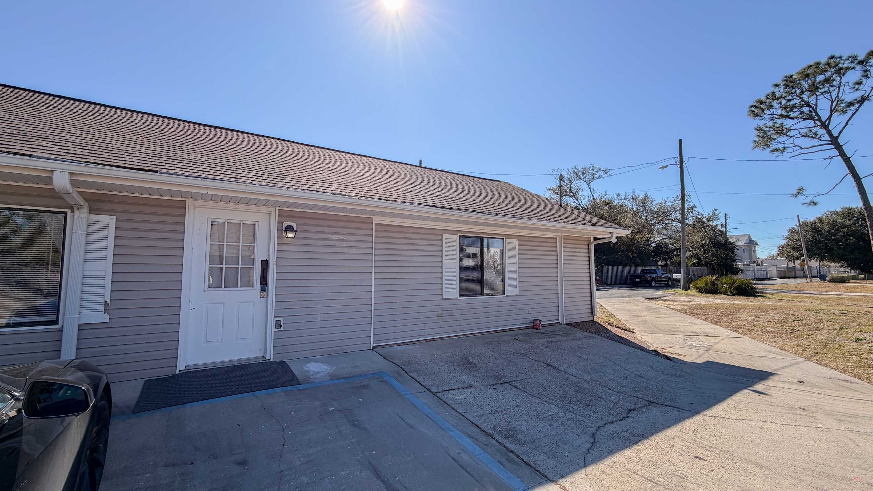 300 W 23rd Pl – Single-story rental exterior with a front door, driveway, and nearby landscaping under a clear blue sky.