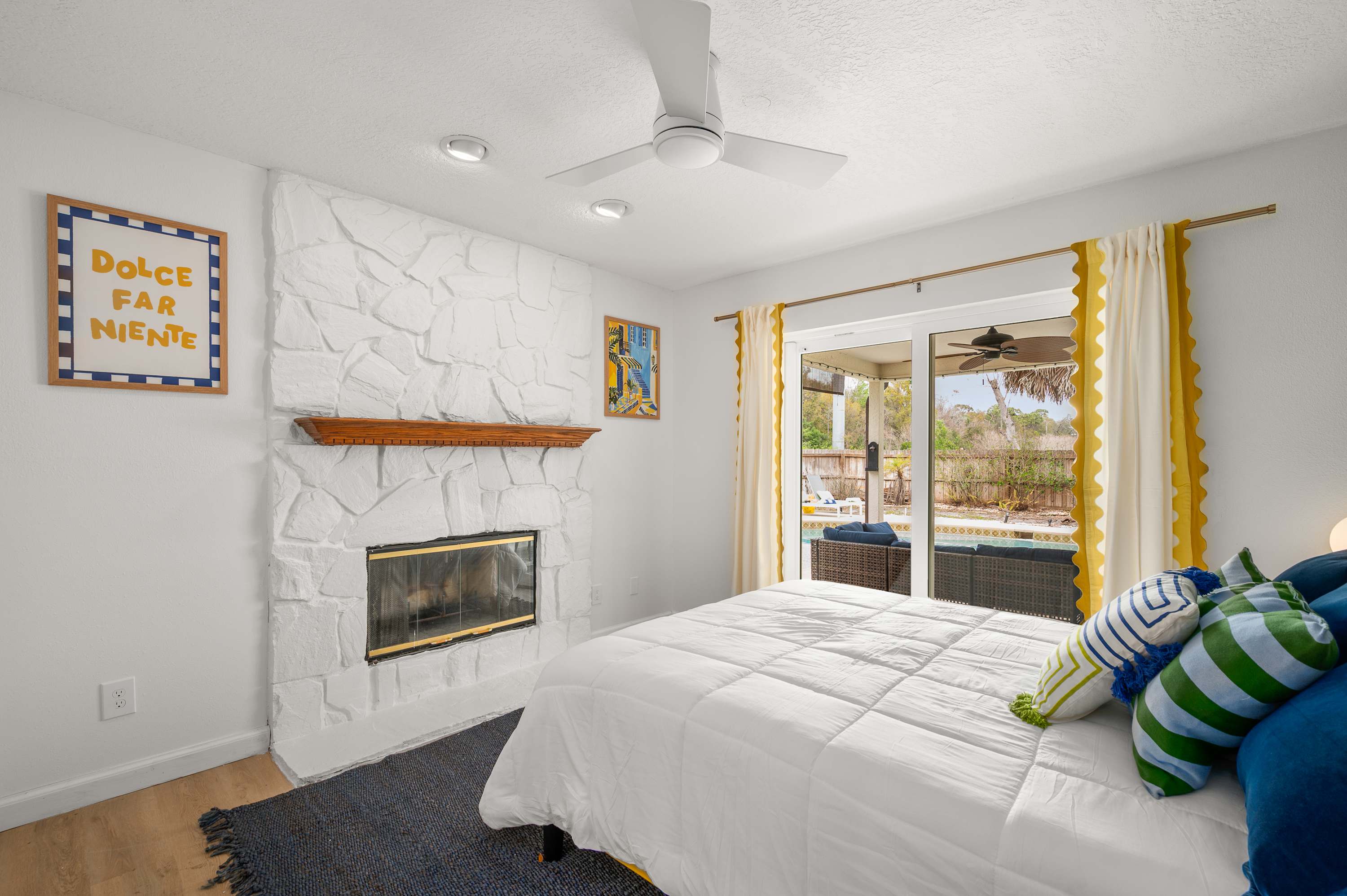 Airy bedroom w/ ceiling fan, a bed & soft blue & yellow accents.