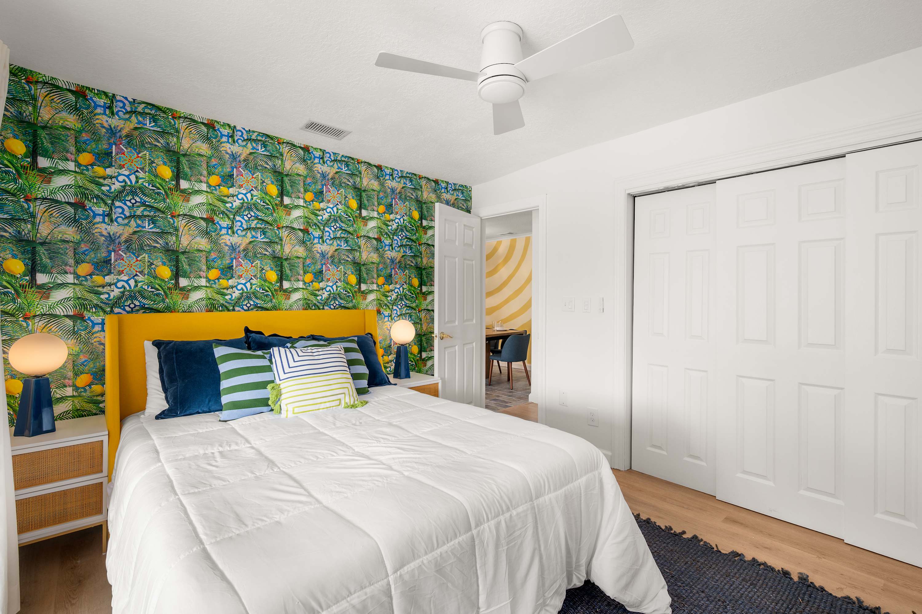 Serene bedroom w/ tropical wallpaper, a bed & soft natural light.