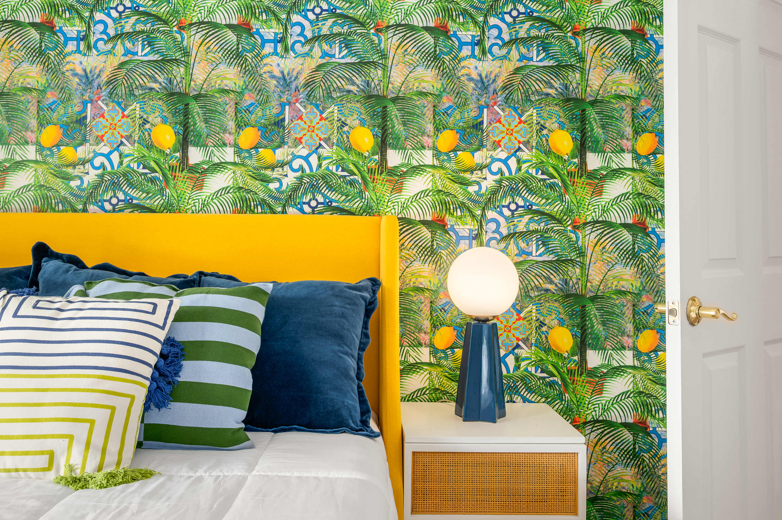 Bold tropical bedroom w/ vivid green & yellow mural wall & cozy bed.