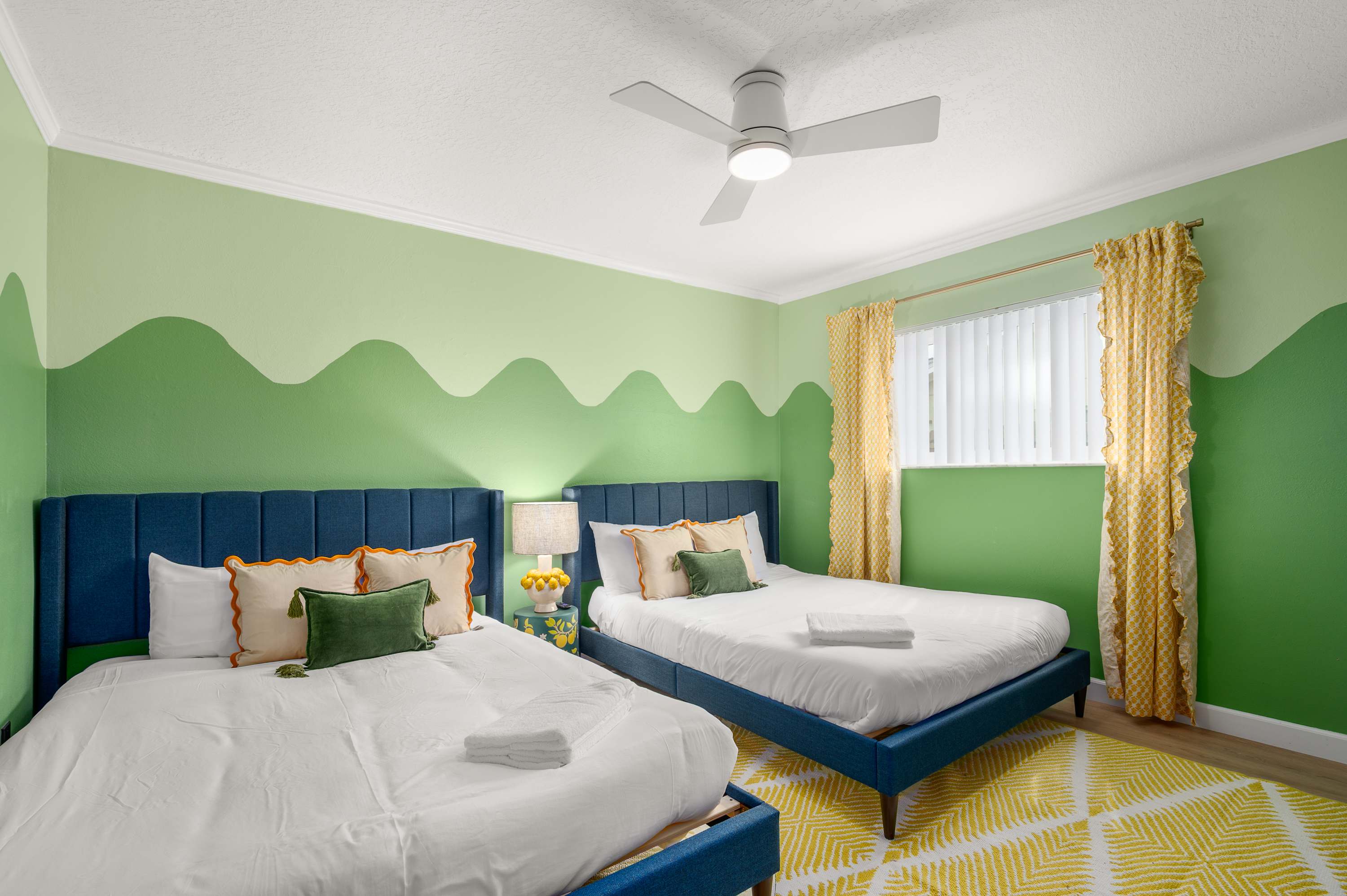 Fresh green bedroom w/ ceiling fan & twin beds dressed in crisp linens.