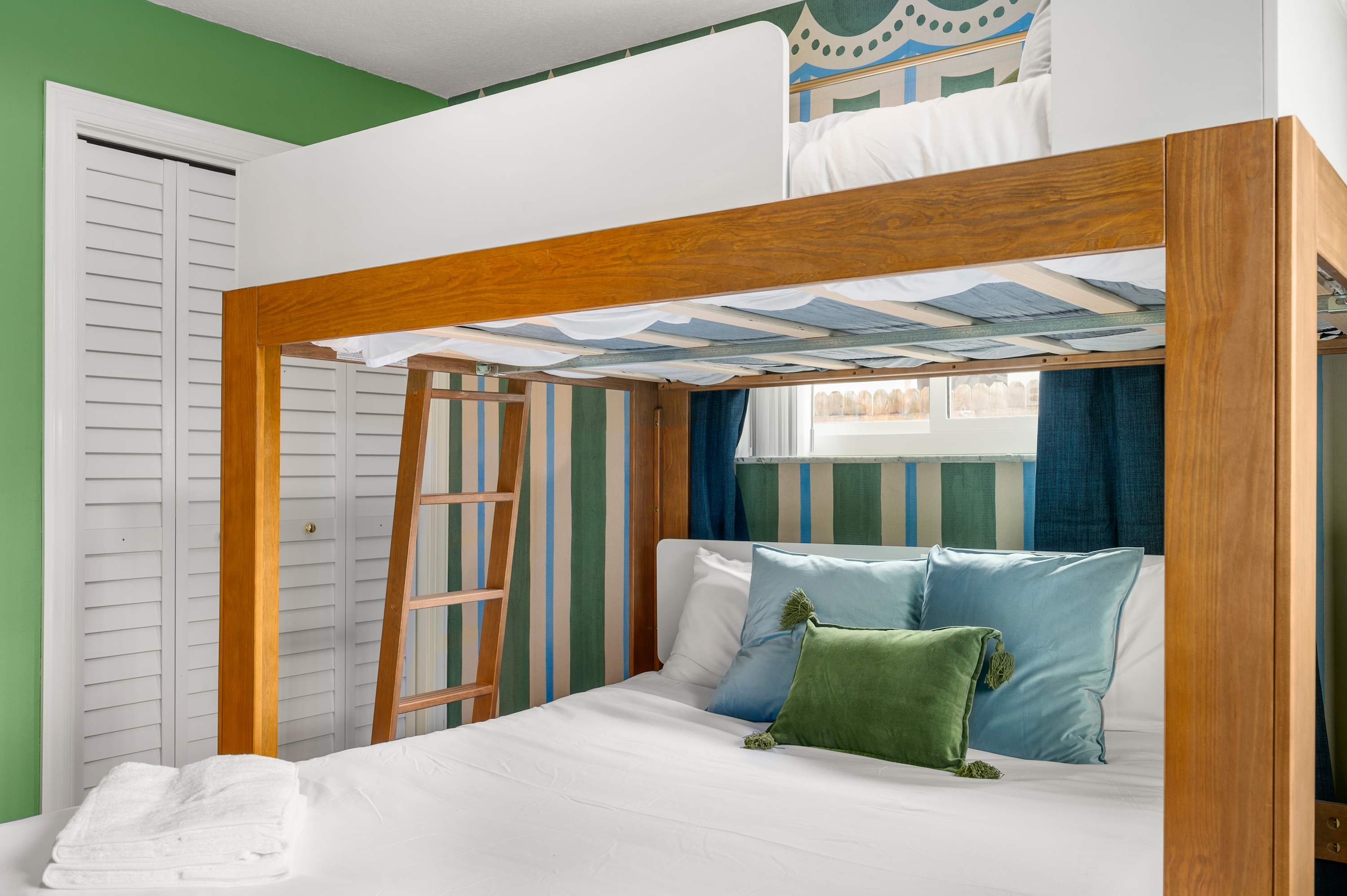 Sunny bunk room w/ two sets of bunks & a large wood-framed mirror.