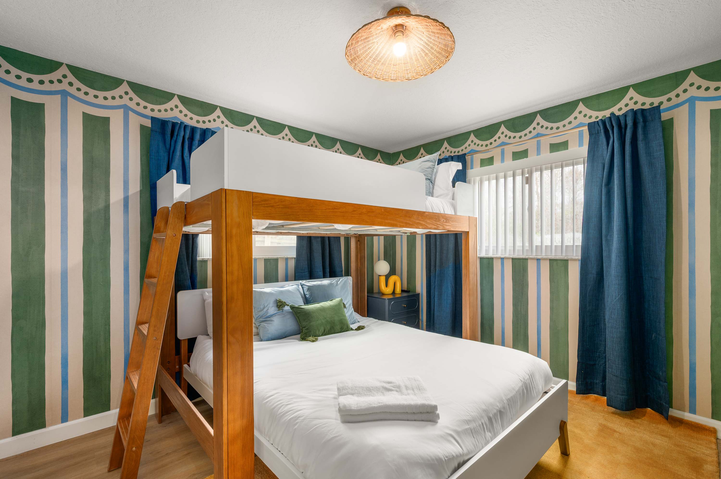Playful bunk room w/ two sets of bunks & colorful curtains for each bunk.