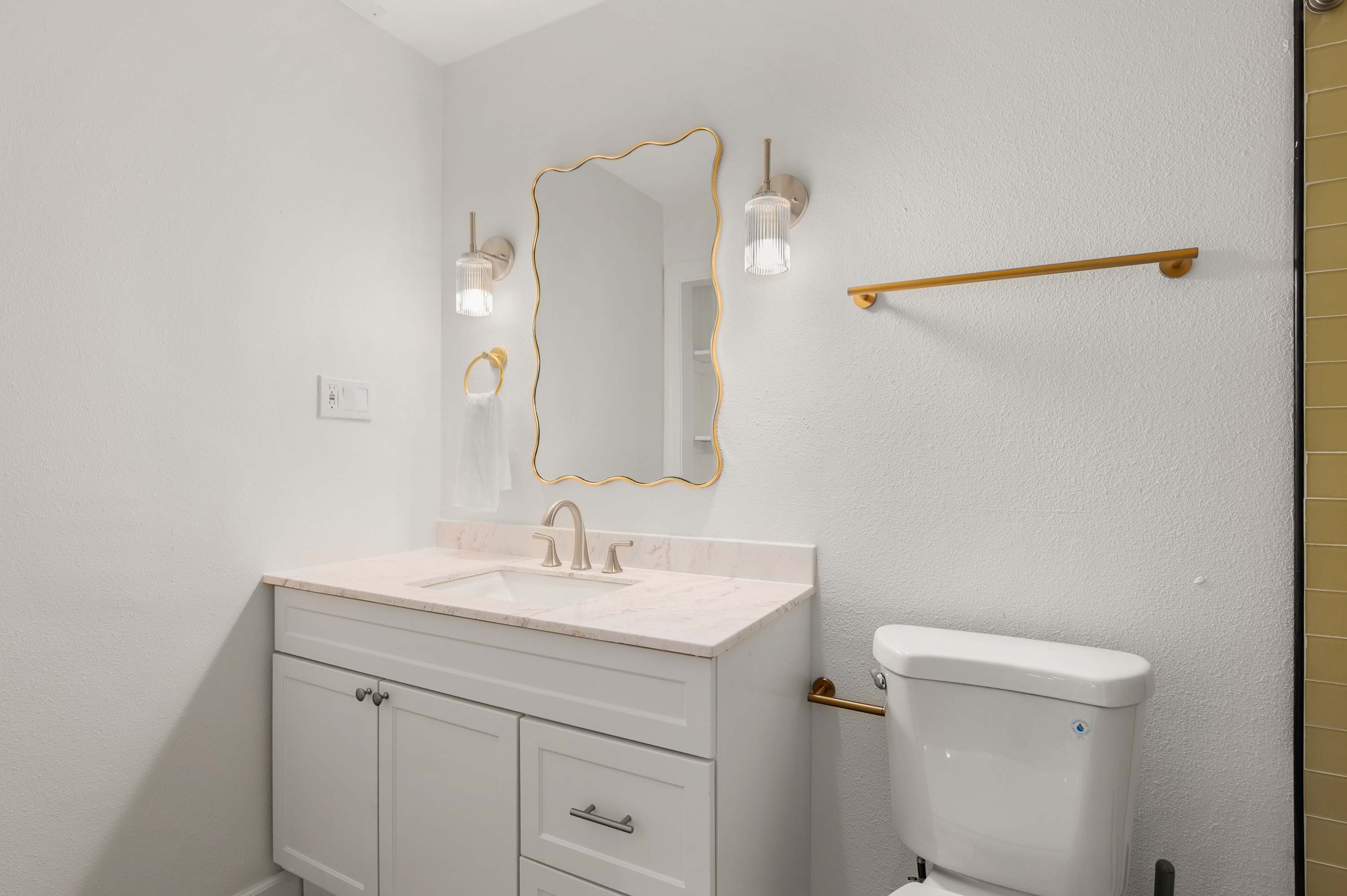 Bright bathroom w/ sink, mirror & soft wall sconce lighting.