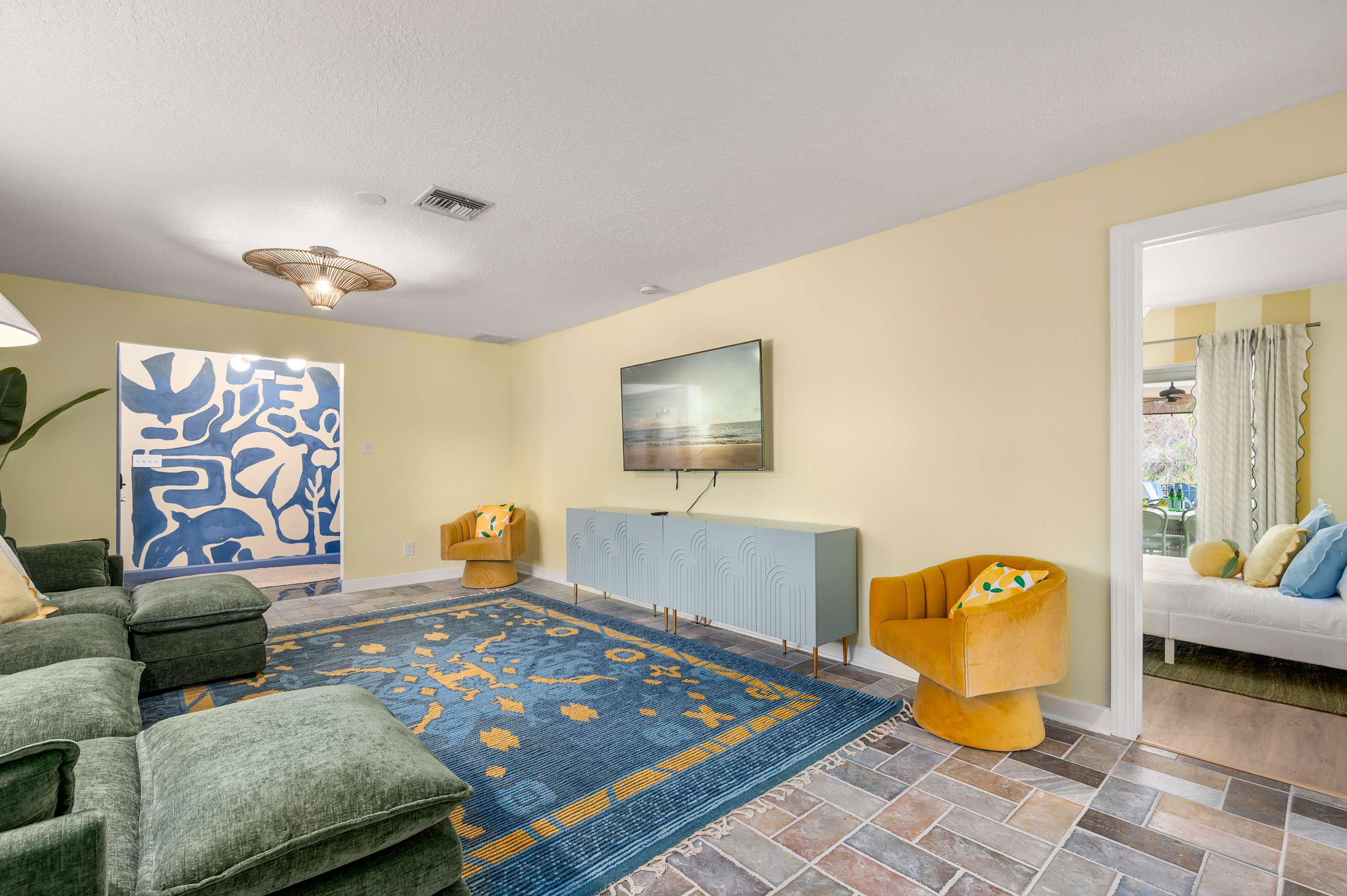 Open living & dining area w/ bold blue rug, ceiling fan & cheerful decor.