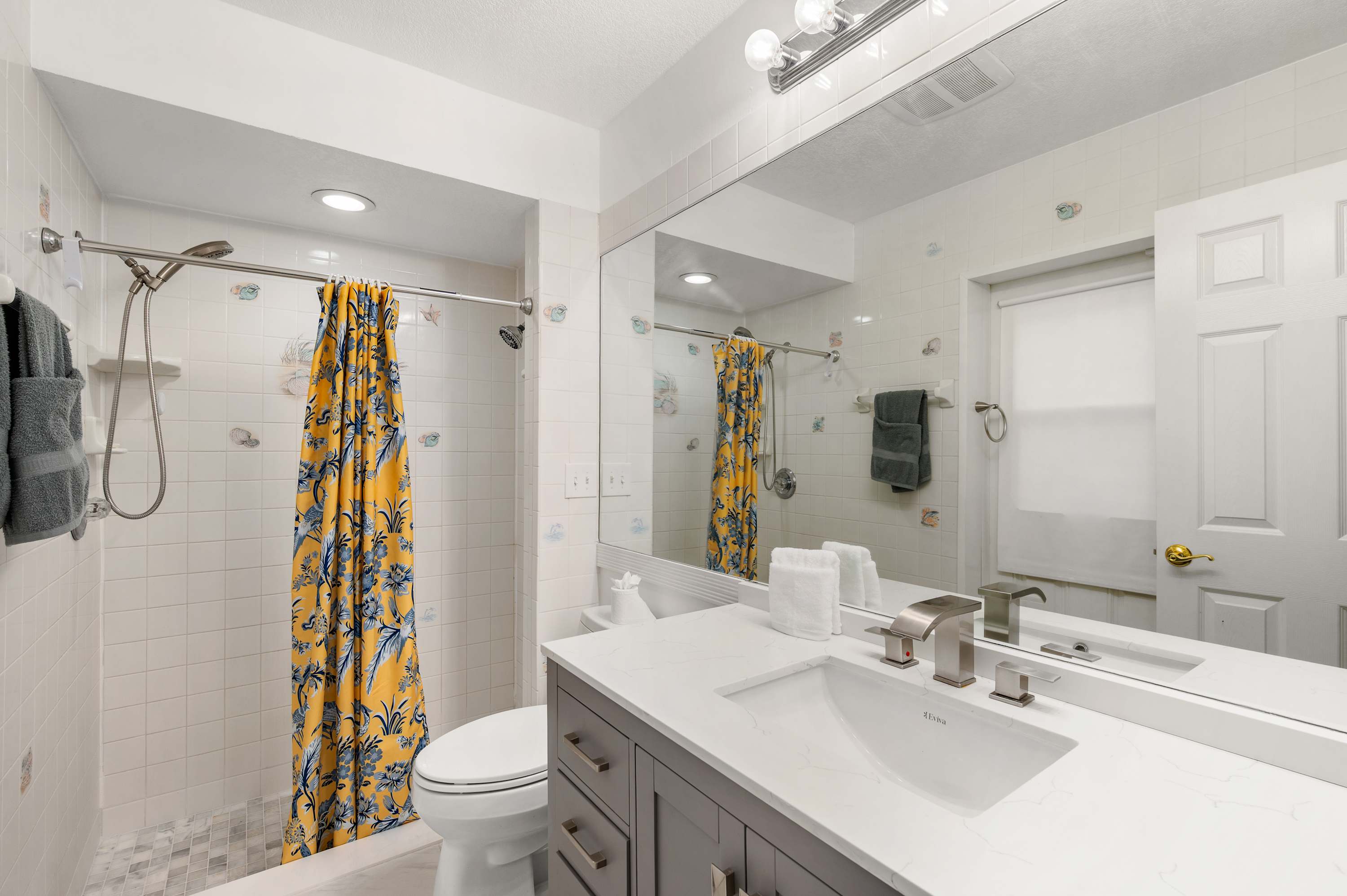 Bathroom w/ double sink vanity, shower curtain & warm natural light.