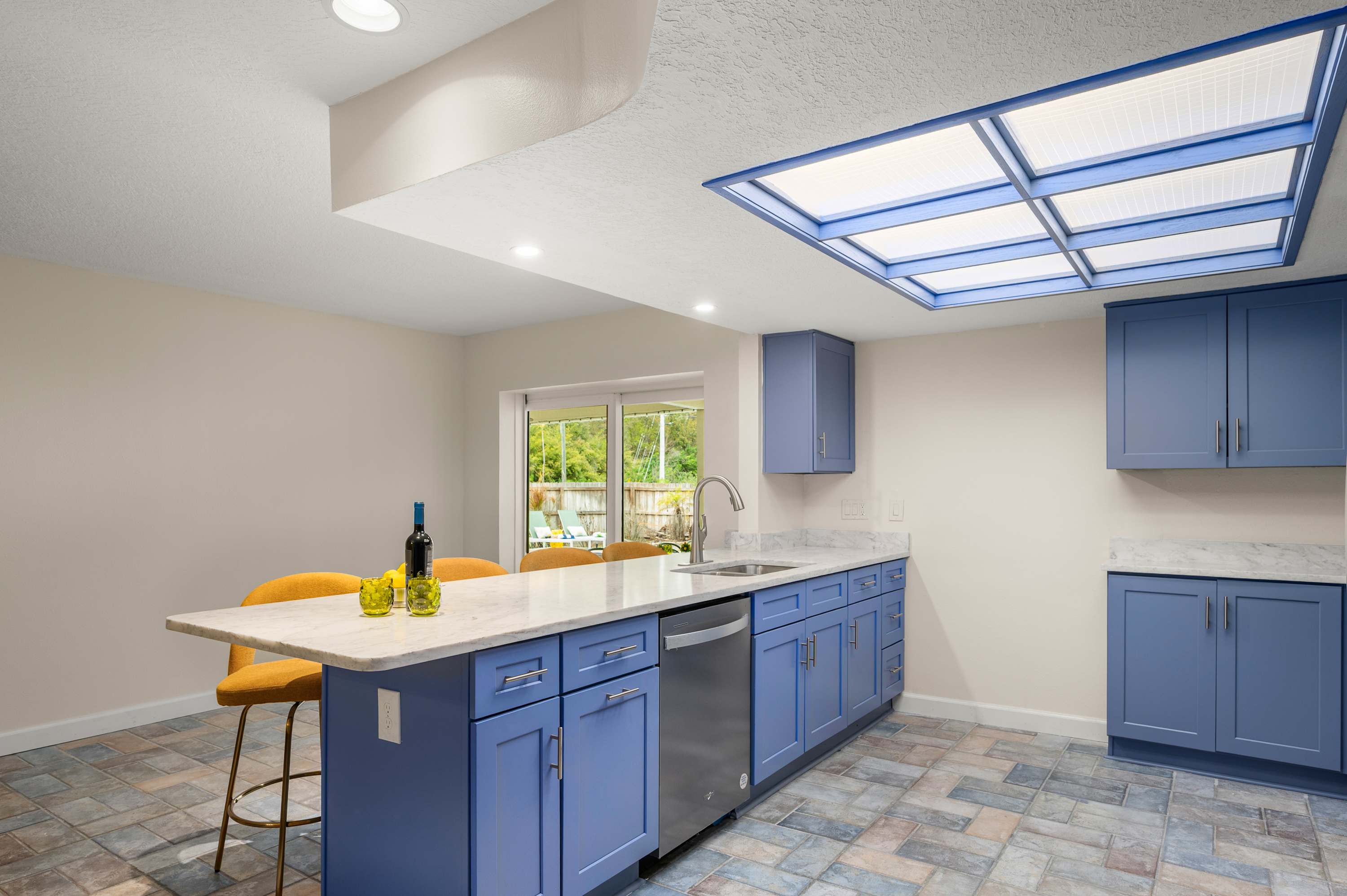 Spacious kitchen w/ blue island, skylights & tile flooring.