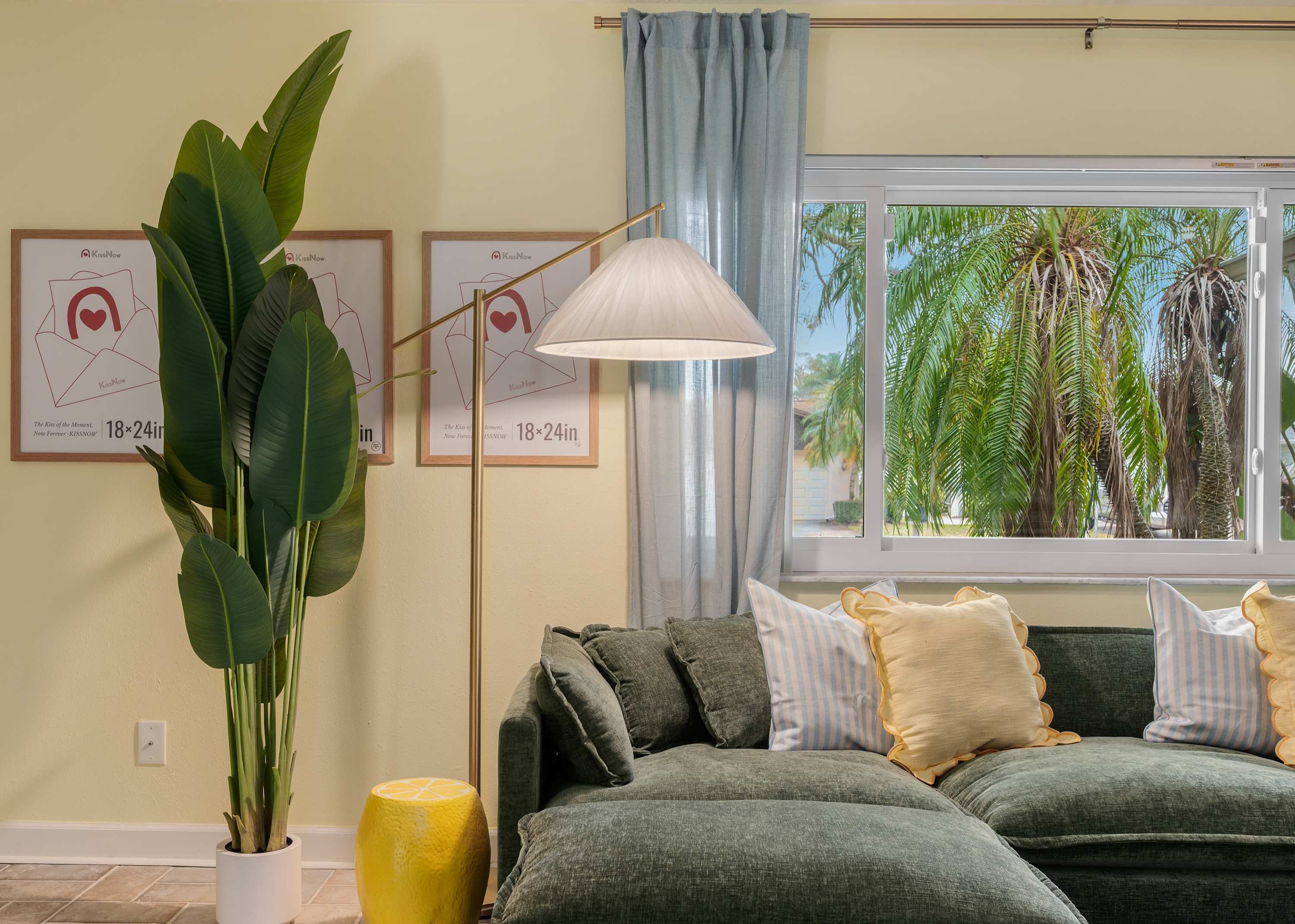 Bright living area w/ tall plant, teal curtains & plenty of natural light.