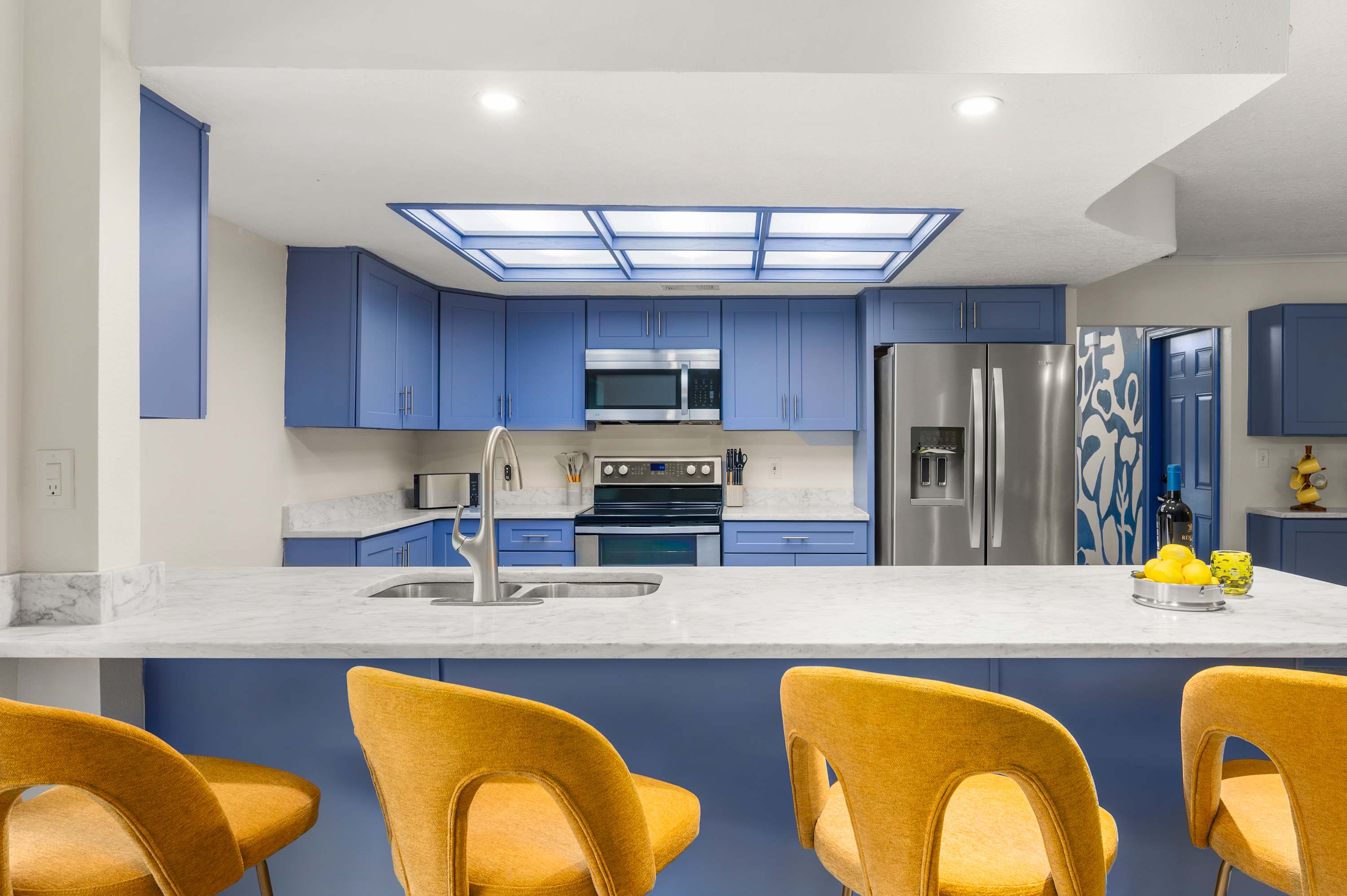 Kitchen island w/ yellow bar stools — a great spot for casual meals & morning coffee.
