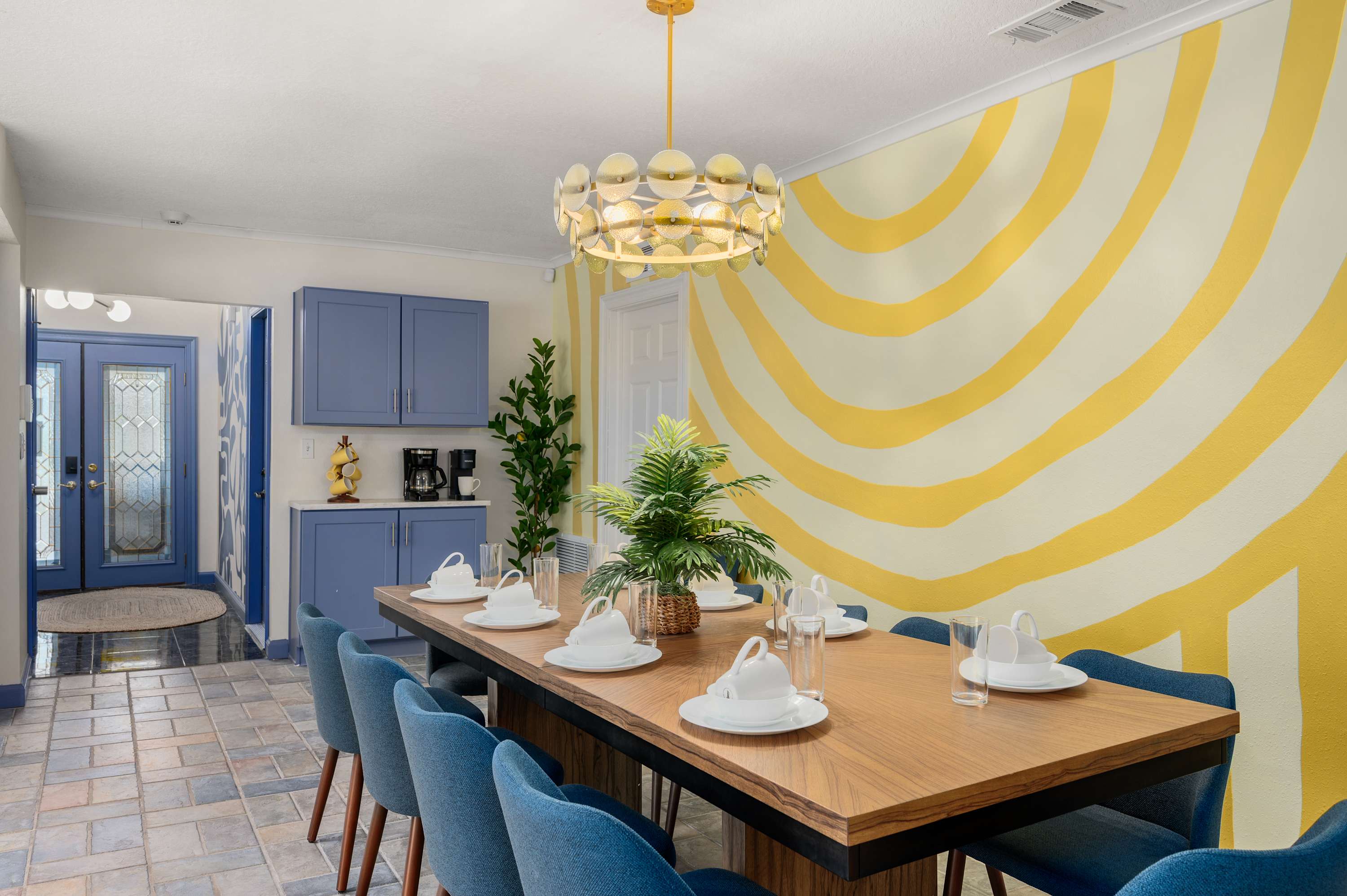 Dining space w/ a long wood table, set & ready for a group meal.