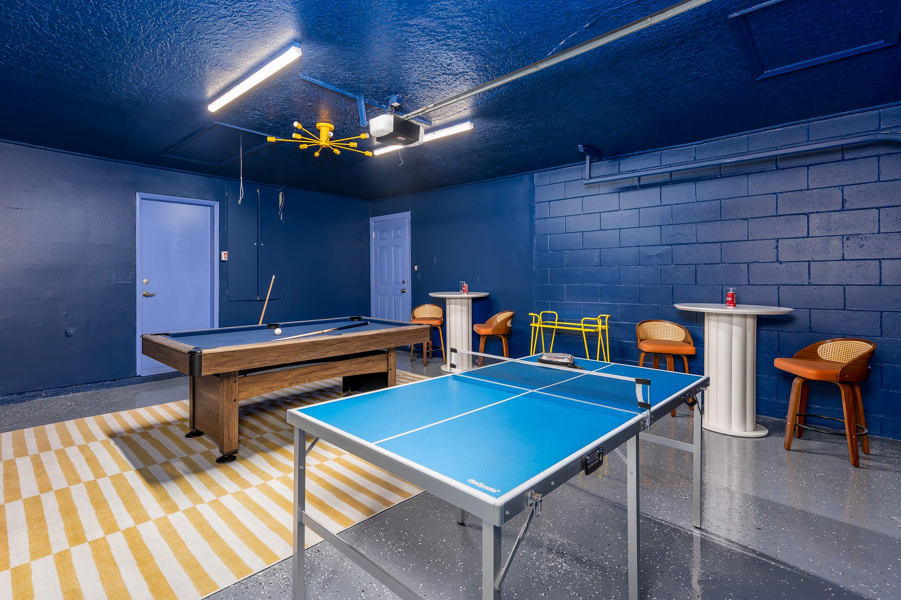 Game room w/ ping pong table, neon lighting & bold blue decor.
