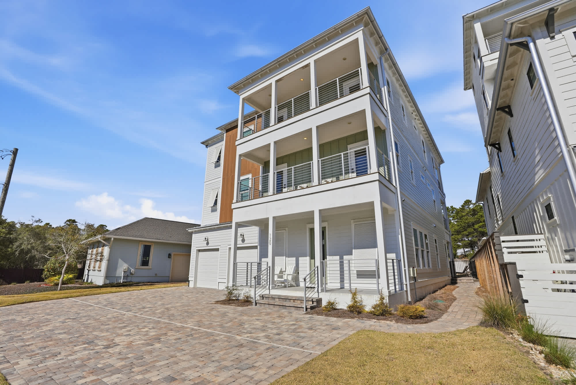 120 Dune Drive – Three-story vacation rental with a front porch, balconies, and a paved driveway.