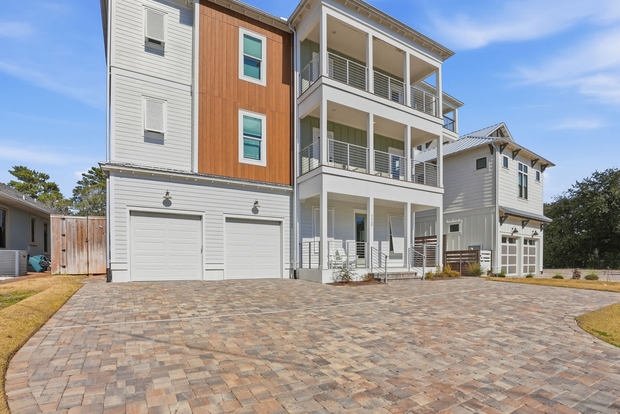 120 Dune Drive – Three-story vacation rental with a large driveway, garage doors, and a covered balcony.
