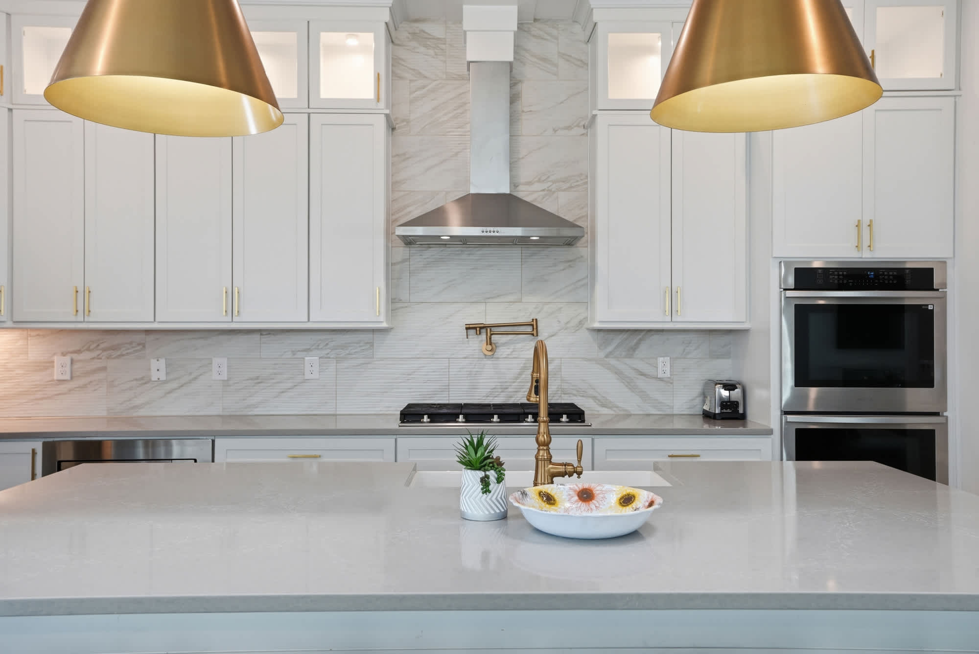 120 Dune Drive – Modern kitchen featuring a large island, stainless steel appliances, and gold pendant lights.