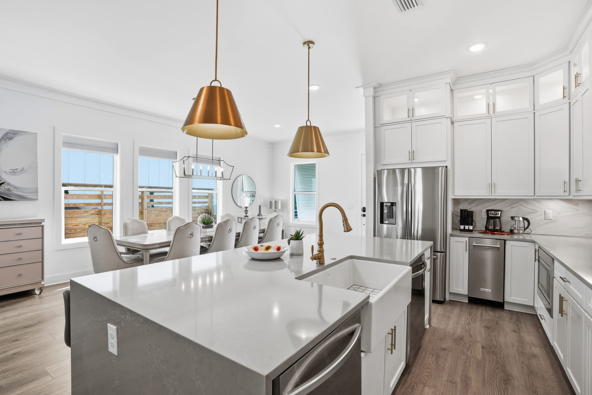 120 Dune Drive – Modern kitchen with an island, dining area, white cabinetry, and large windows showing a view outside.