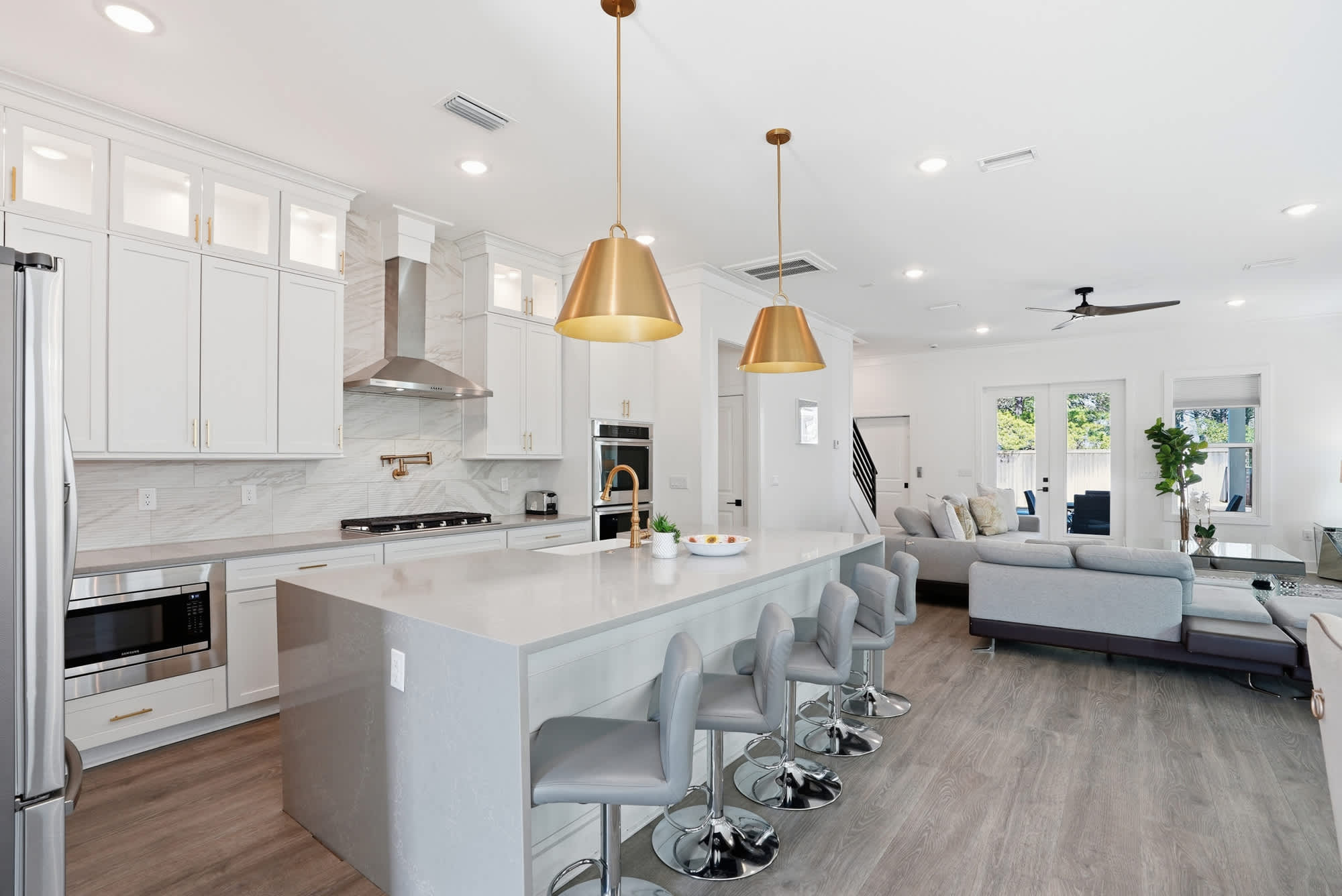 120 Dune Drive – Bright open kitchen with white cabinets, stainless steel appliances, and a living area with a sectional sofa.