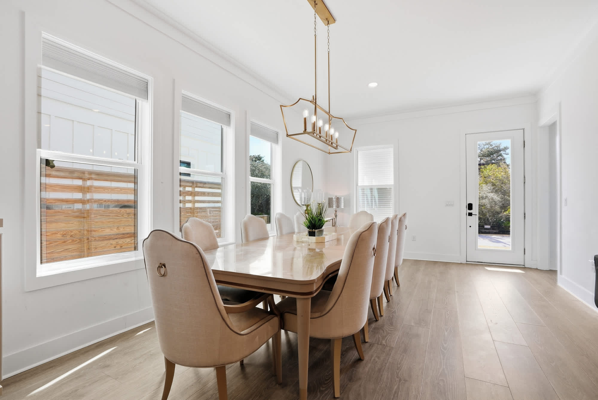 120 Dune Drive – Dining room with a long wooden table, plush chairs, and large windows providing natural light.