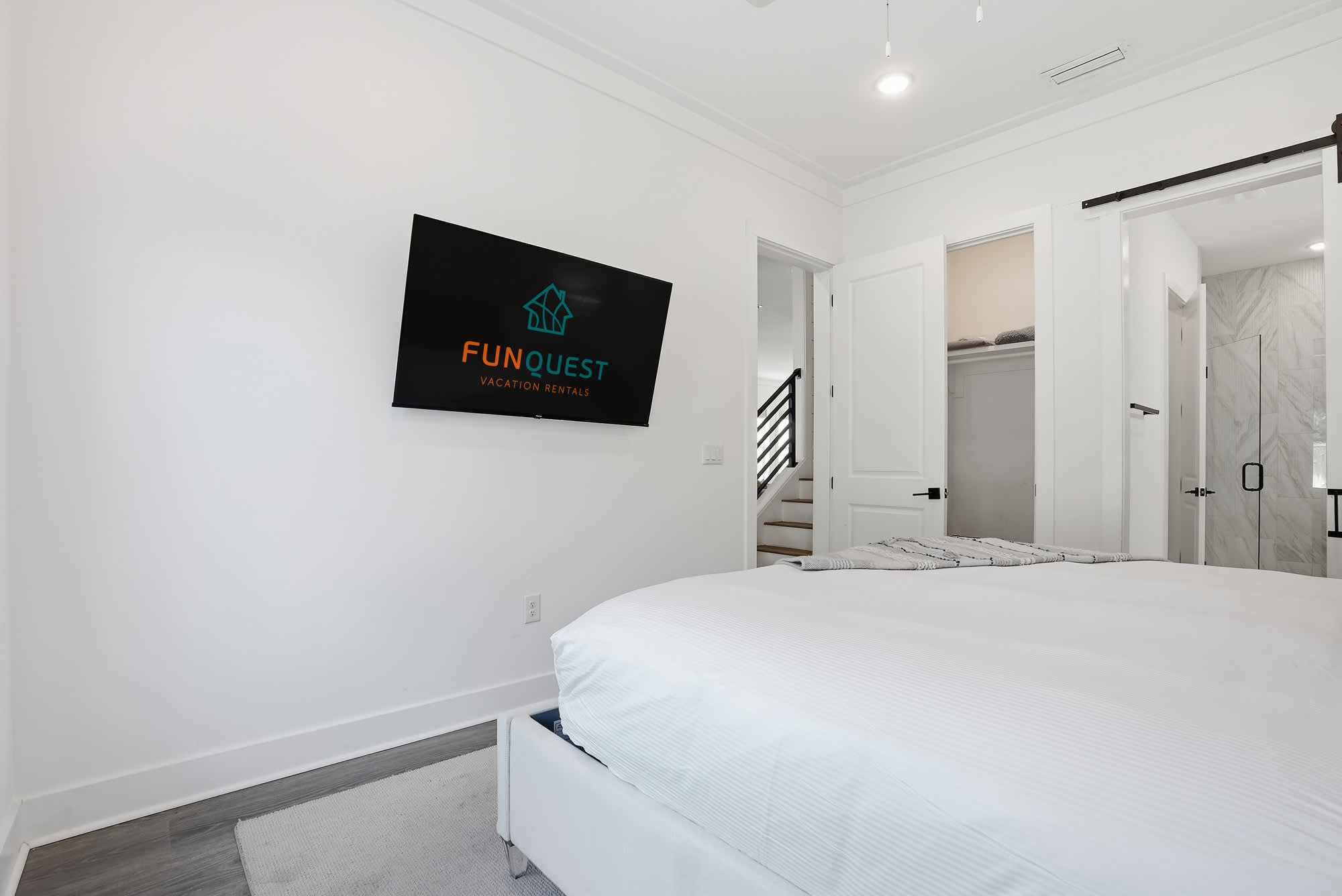 120 Dune Drive – Bright bedroom with a large wall-mounted TV and an en-suite bathroom view.
