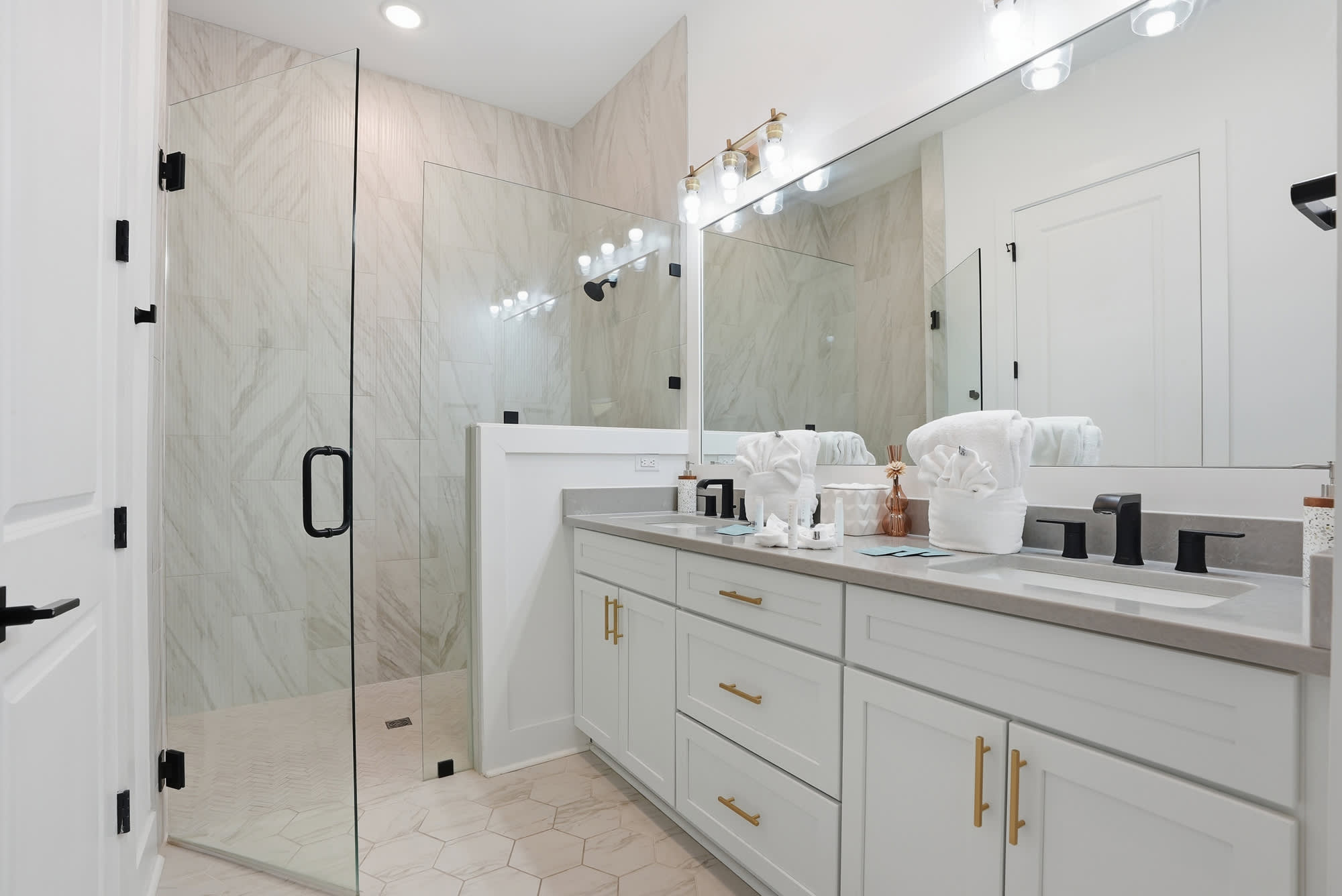 120 Dune Drive – Modern bathroom with glass shower, double vanity, stylish lighting, and elegant tile accents.
