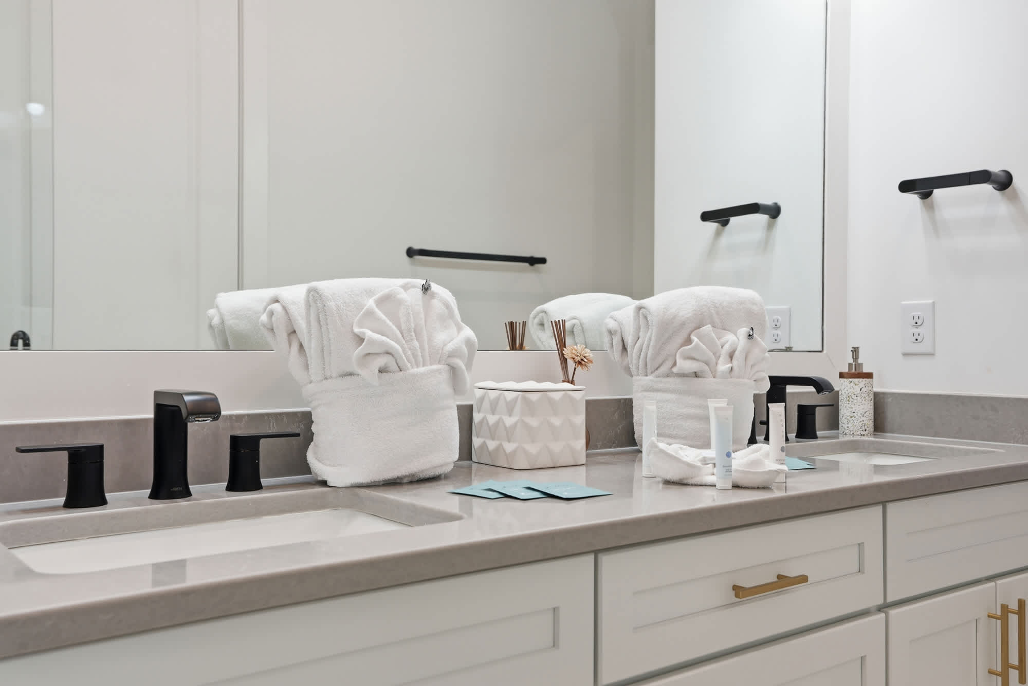 120 Dune Drive – Modern bathroom with double sinks, black fixtures, white towels, and decorative items on the countertop.