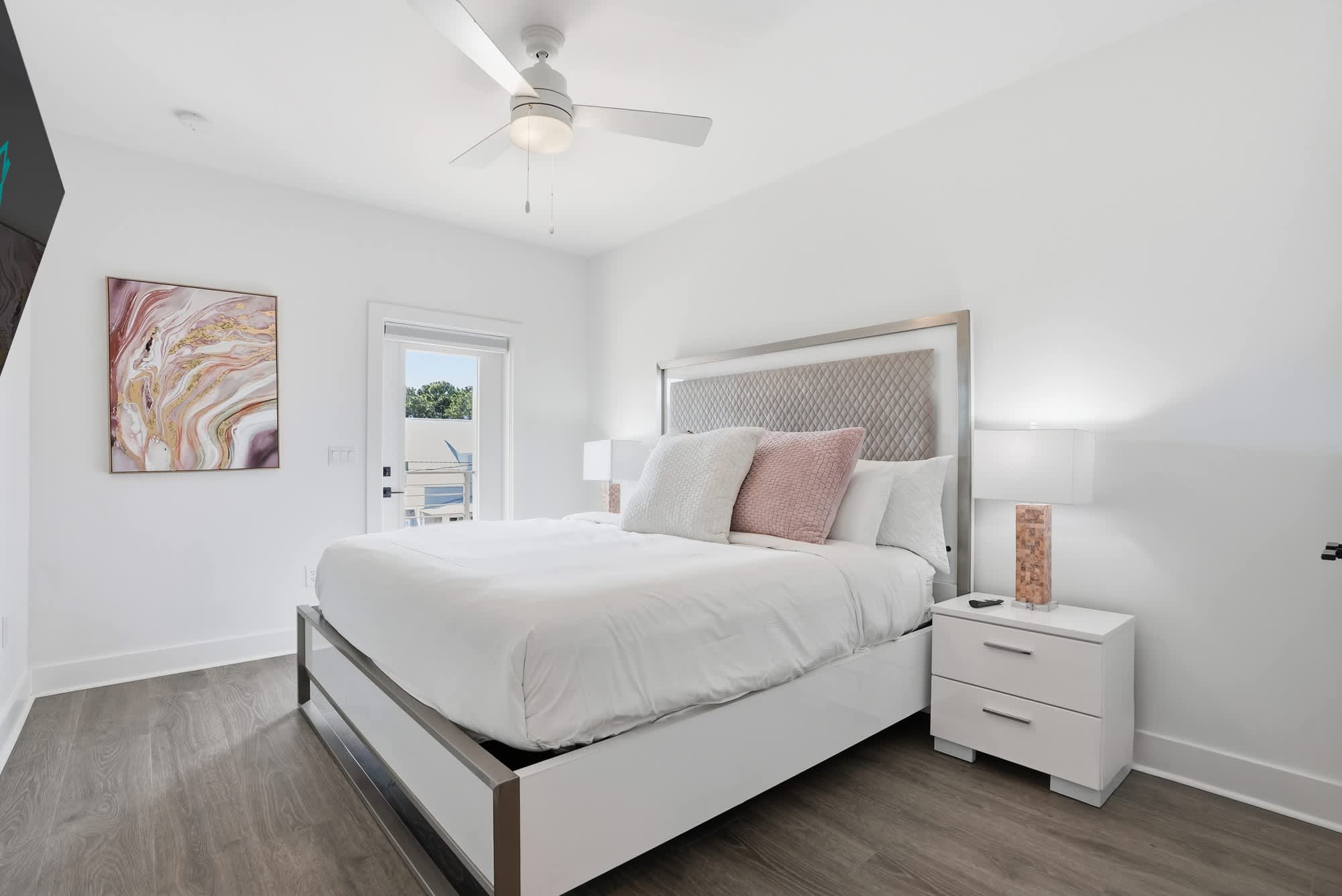 120 Dune Drive – Bright bedroom with a queen bed, nightstands, ceiling fan, and door leading to a balcony.