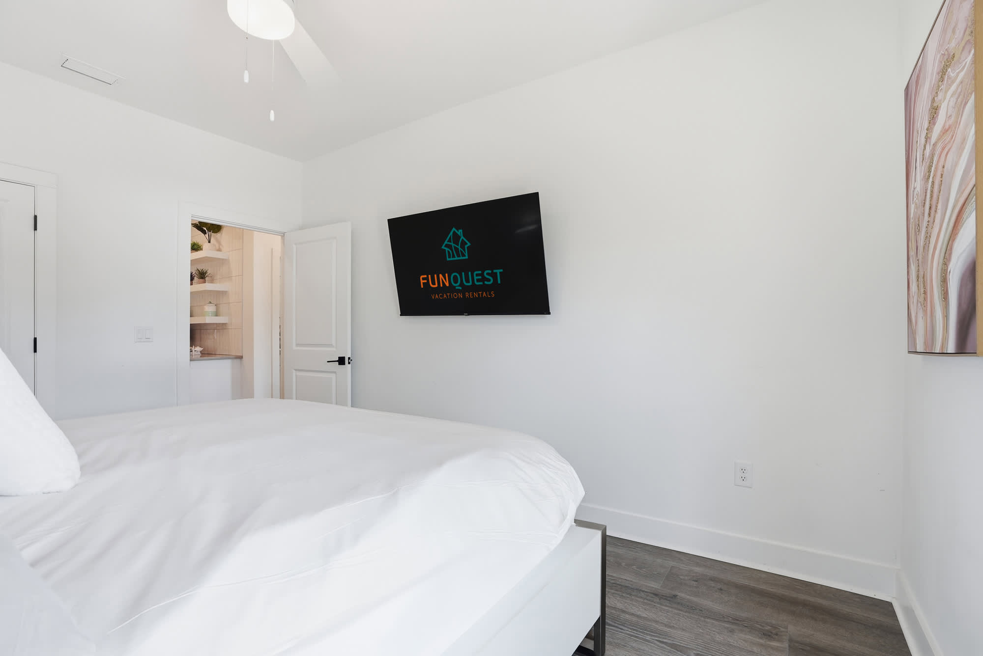 120 Dune Drive – Bedroom with a large bed, wall-mounted TV, and a glimpse of an adjoining room.