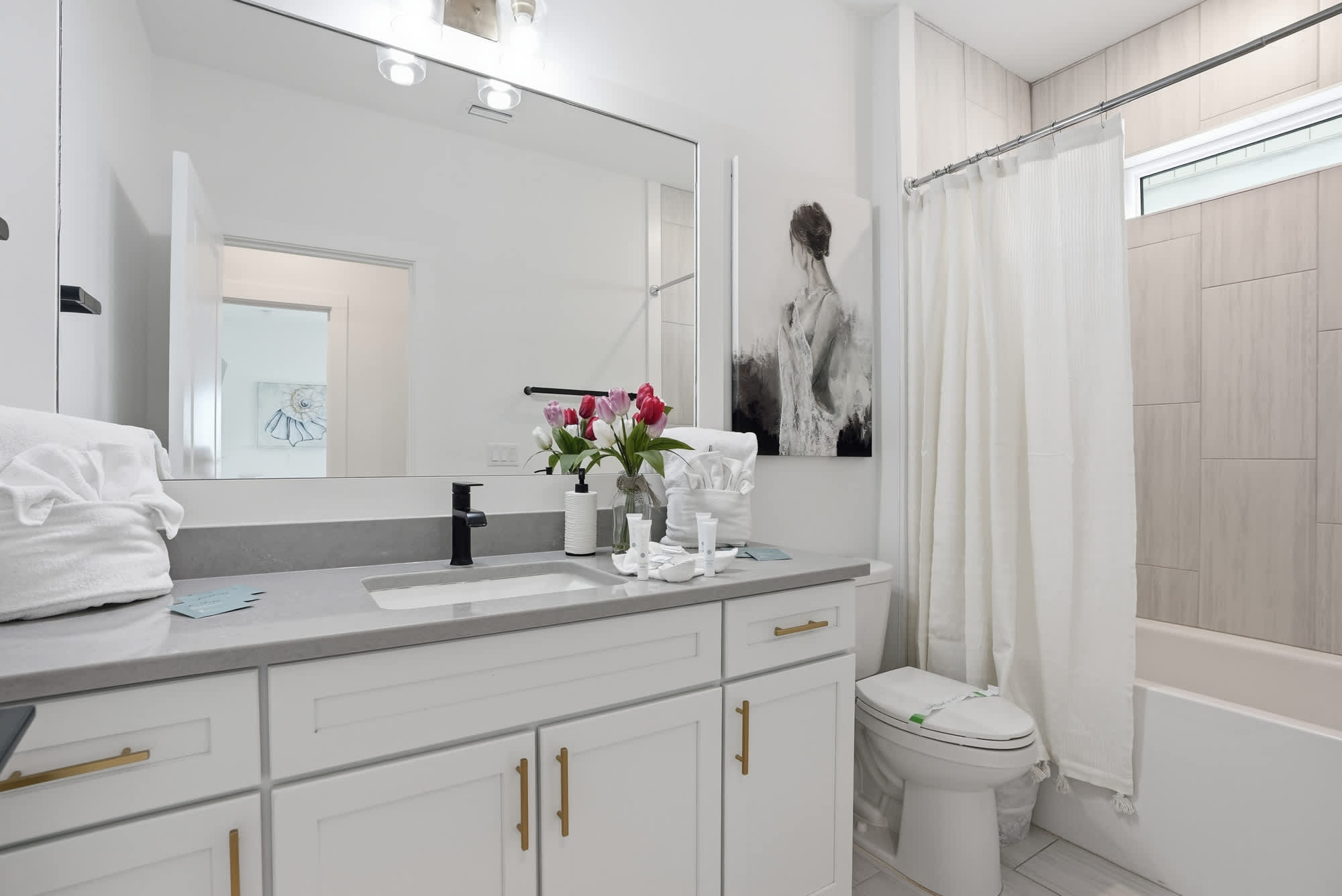 120 Dune Drive – Modern bathroom with a double sink, floral arrangement, and a shower curtain.