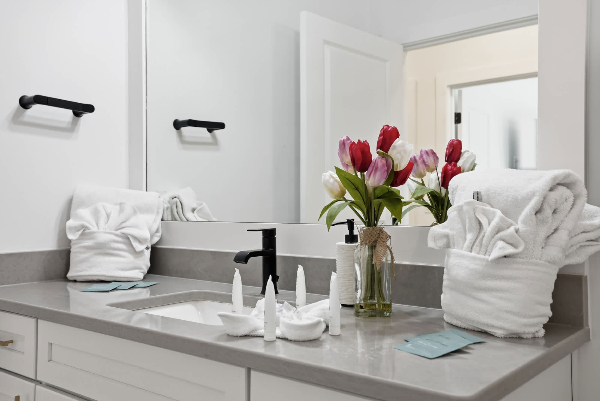 120 Dune Drive – Bathroom with gray countertop, mirror, flowers, and neatly arranged towels.