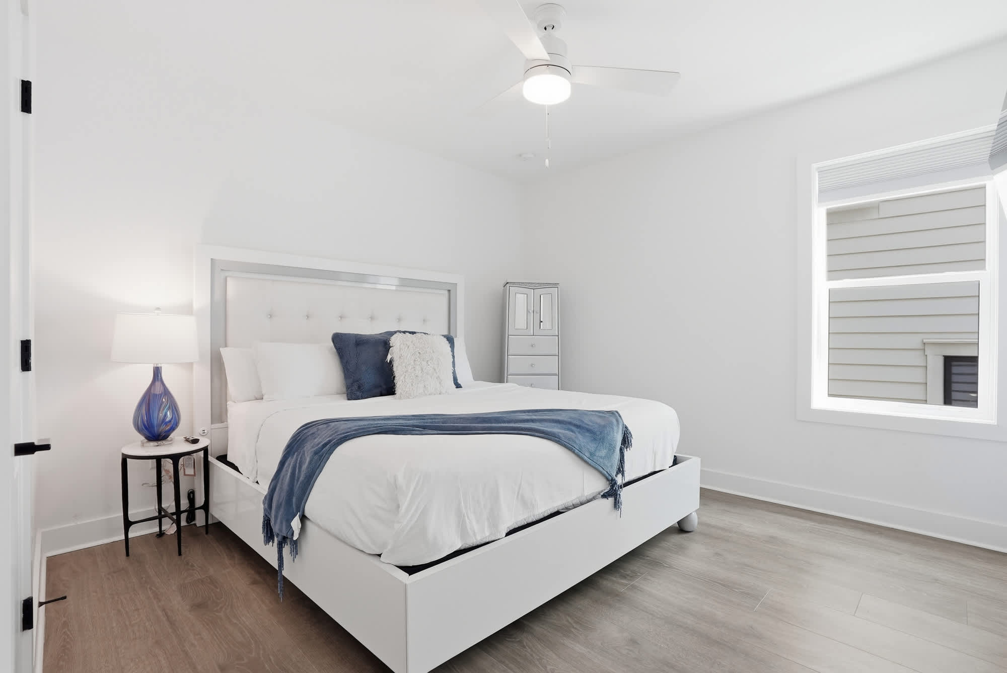 120 Dune Drive – Bright bedroom with a queen bed, bedside table, lamp, and window.