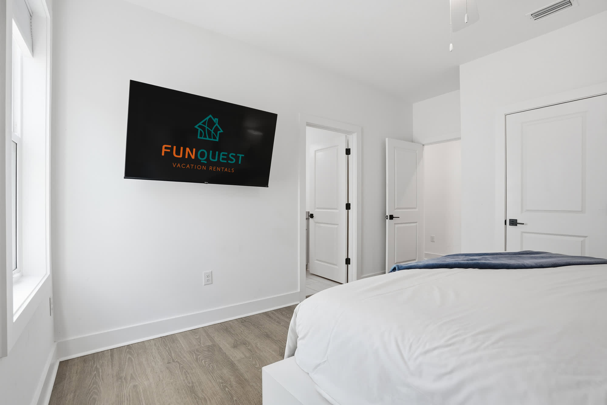 120 Dune Drive – Bedroom with a bed, flat-screen TV, and two doors leading to other rooms.