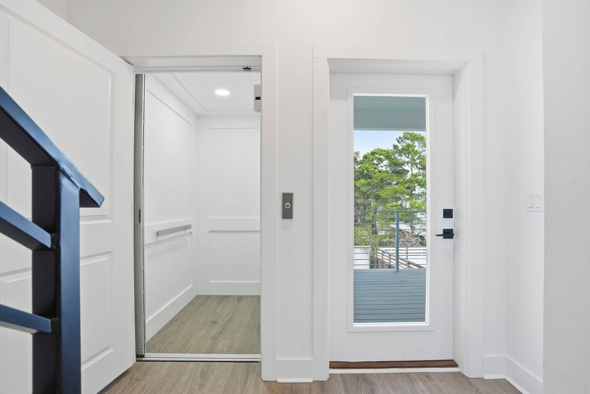 120 Dune Drive – Entryway with an elevator door and a window overlooking a balcony and trees.