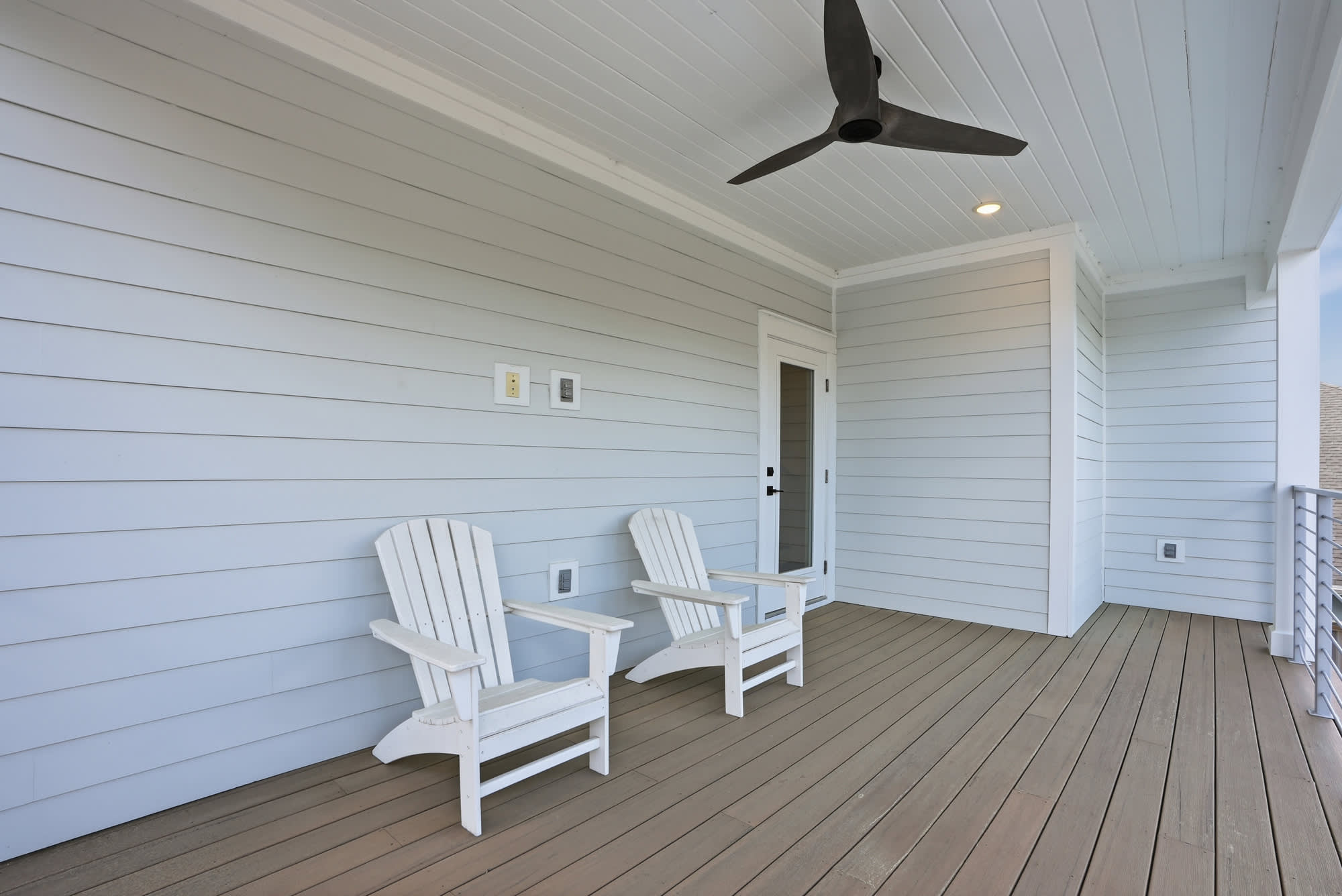 120 Dune Drive – Covered balcony with two white Adirondack chairs and a ceiling fan.