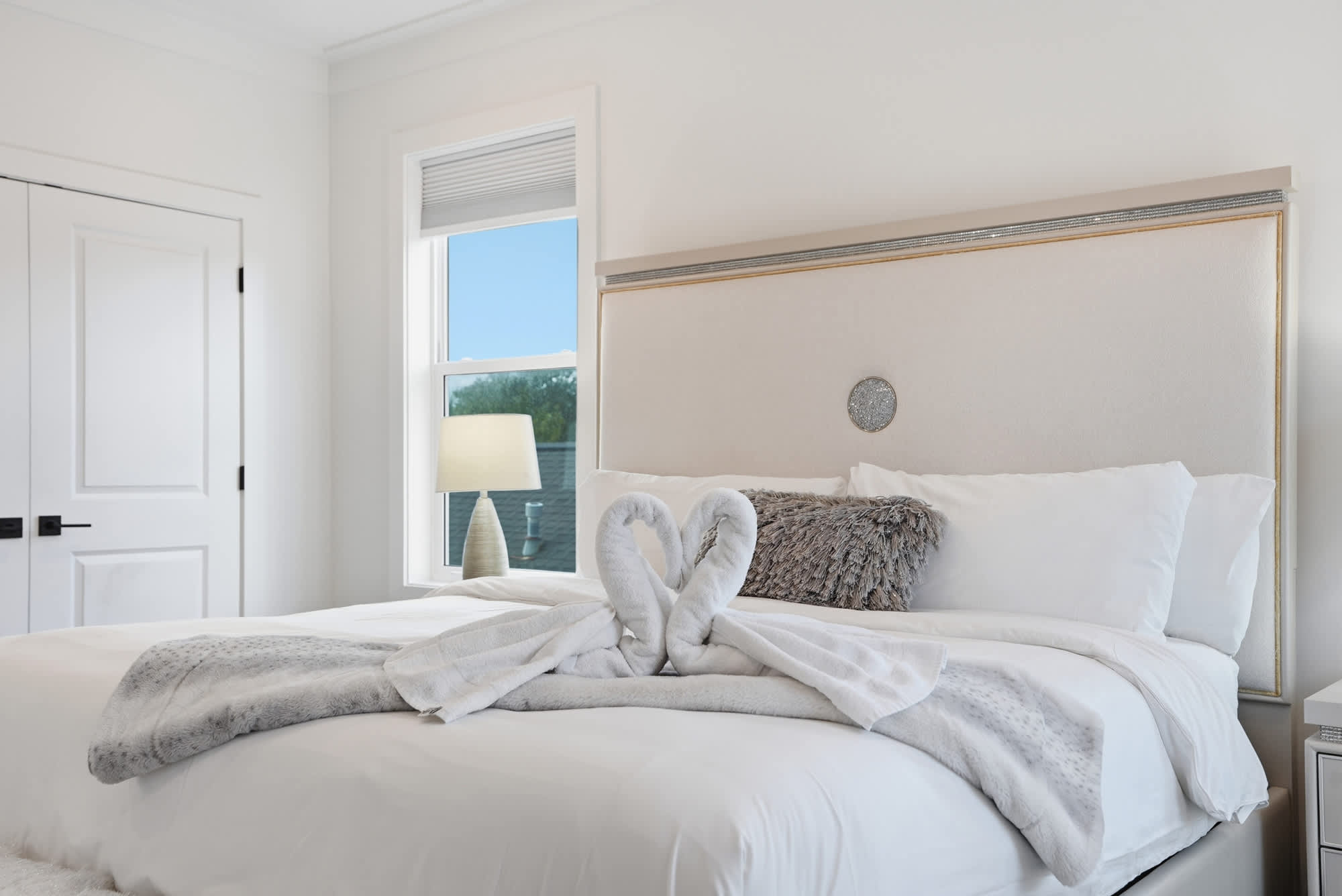 120 Dune Drive – Bright bedroom featuring a large bed, decorative pillows, and a window with a lamp beside it.