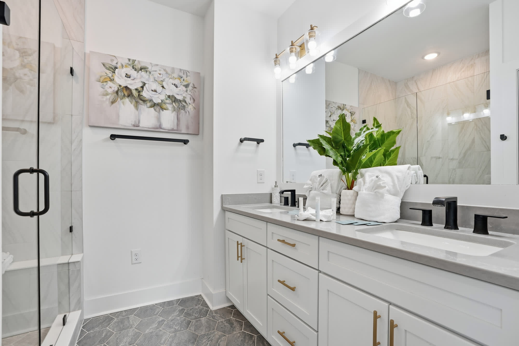 120 Dune Drive – Modern bathroom with a glass shower, double sink vanity, and decorative plant.