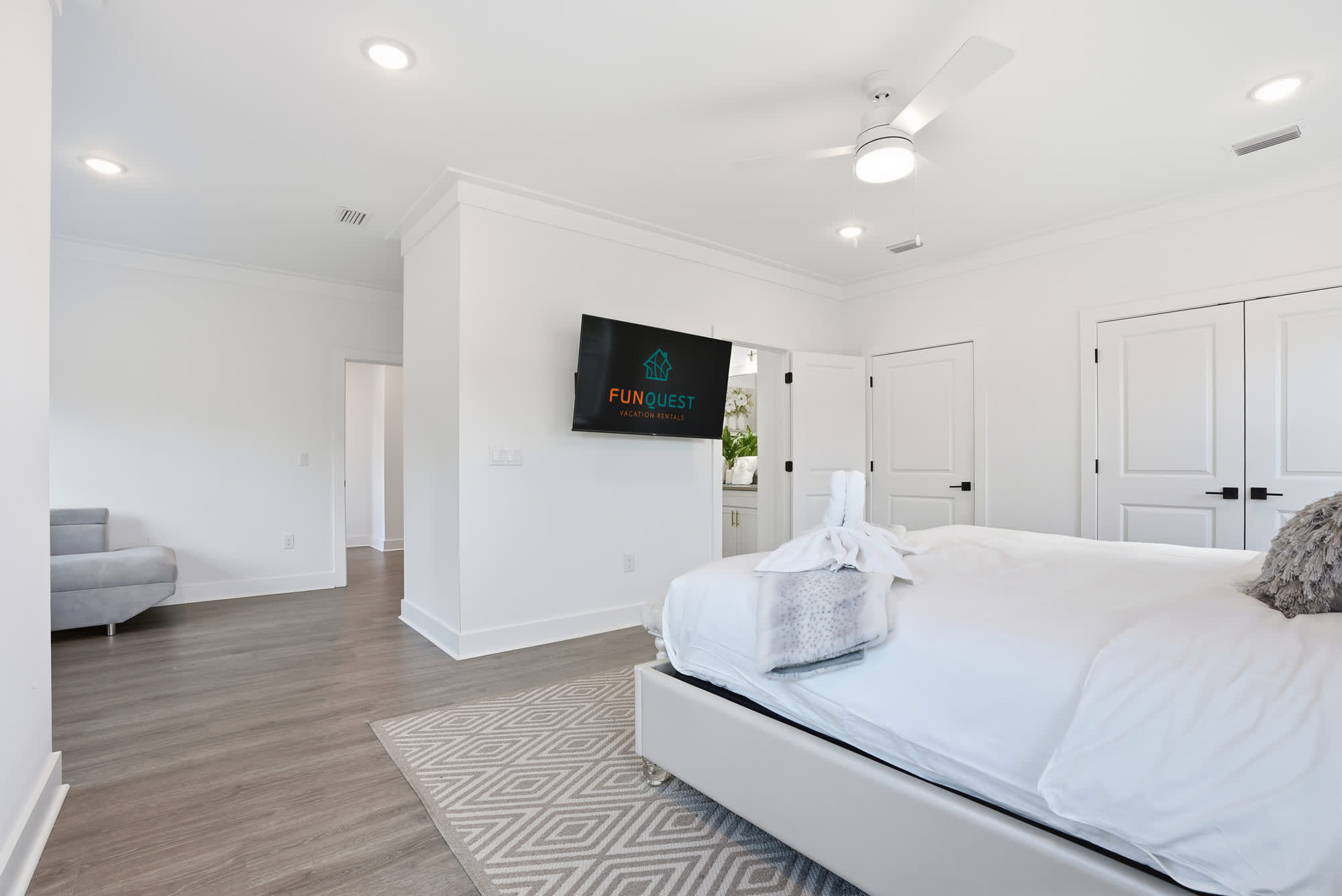 120 Dune Drive – Bright bedroom with a large bed, TV on the wall, and a gray armchair in the corner.