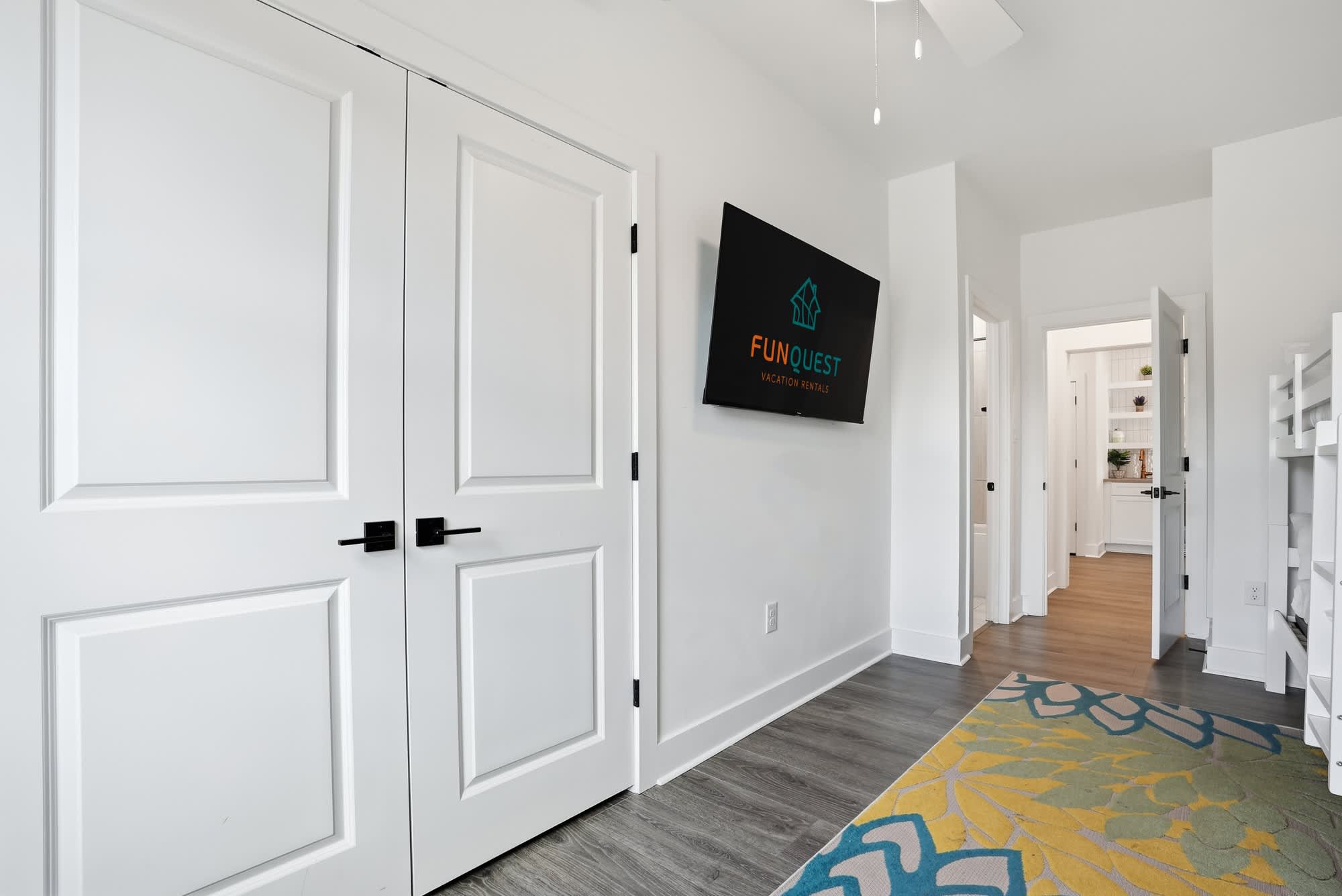 120 Dune Drive – Interior hallway with white doors, flat-screen TV, and decorative area rug.