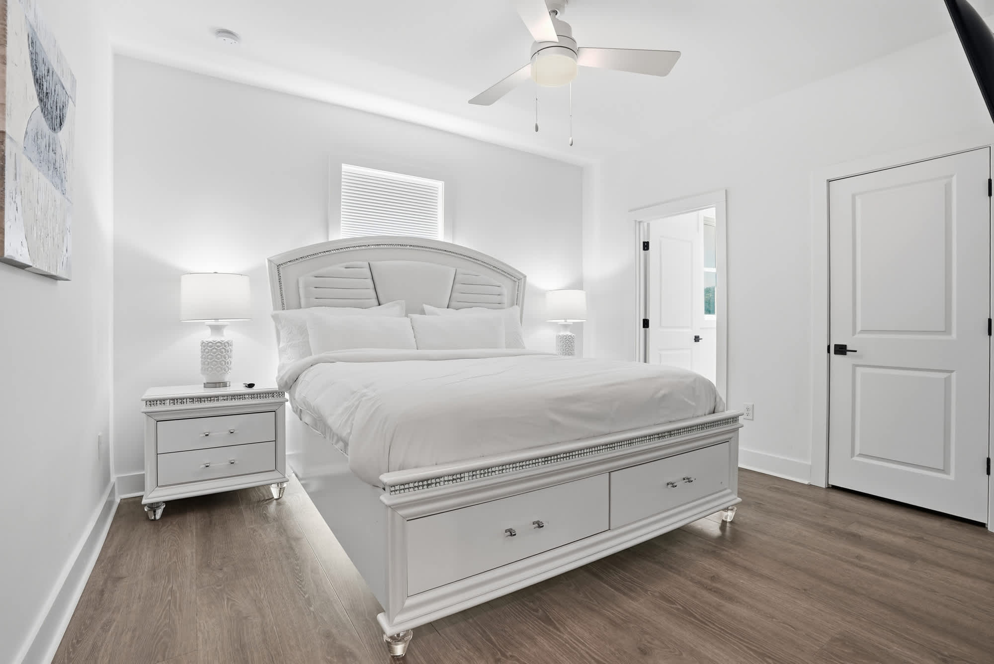 120 Dune Drive – Bright bedroom with a king-sized bed, nightstand, and door leading to hallway.