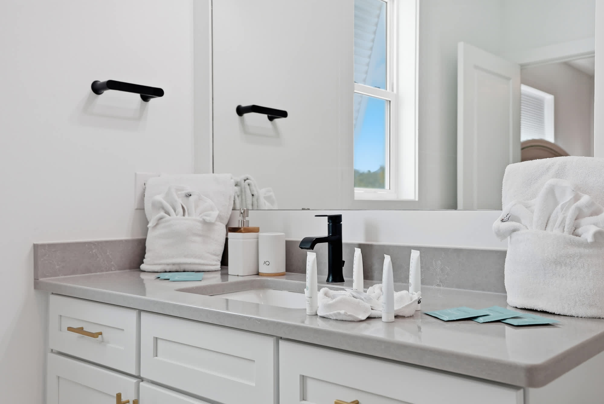 120 Dune Drive – Modern bathroom with a double sink, black faucet, and neatly arranged towels and toiletries.