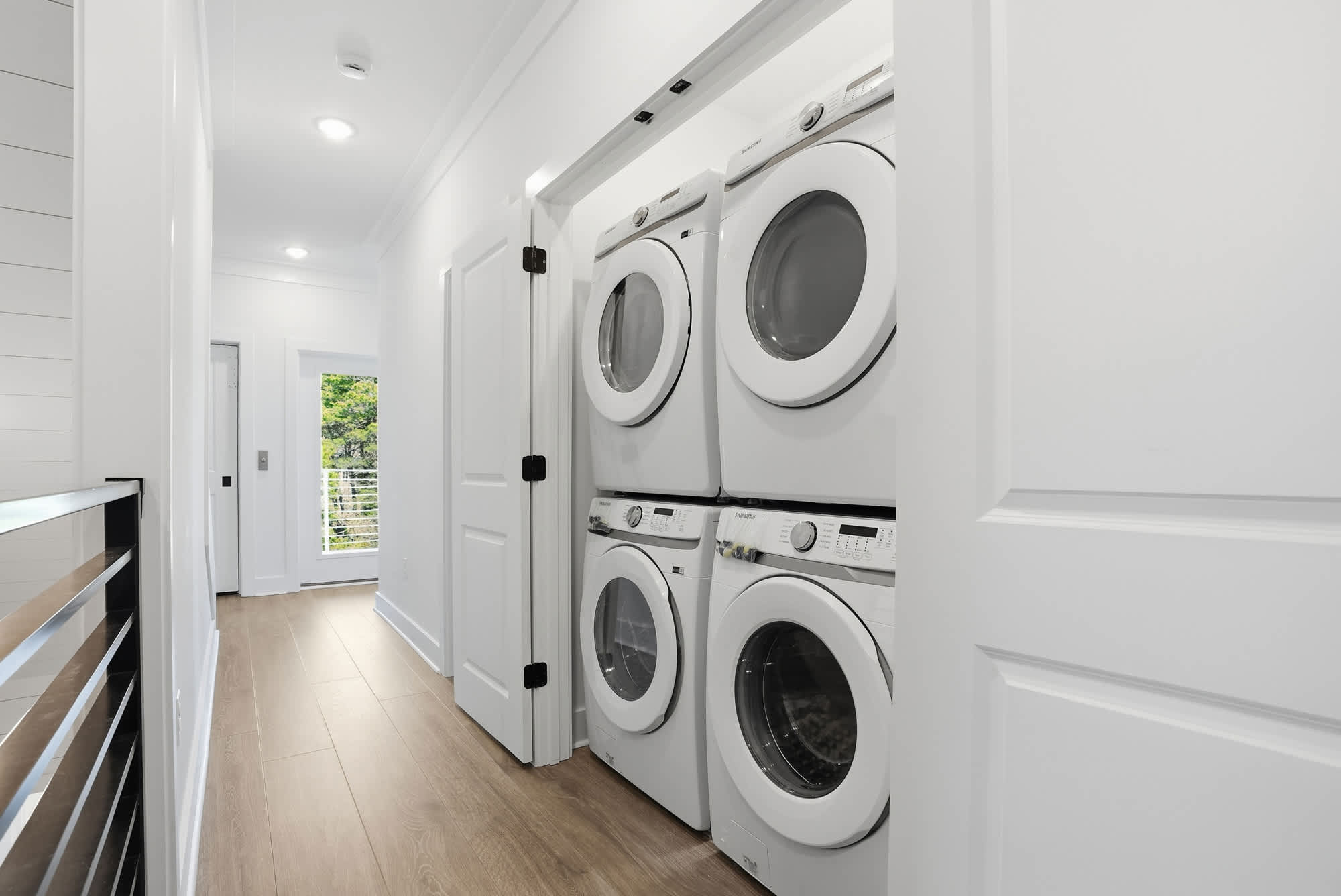 120 Dune Drive – Laundry area with stacked washer and dryer, white walls, and a window providing natural light.