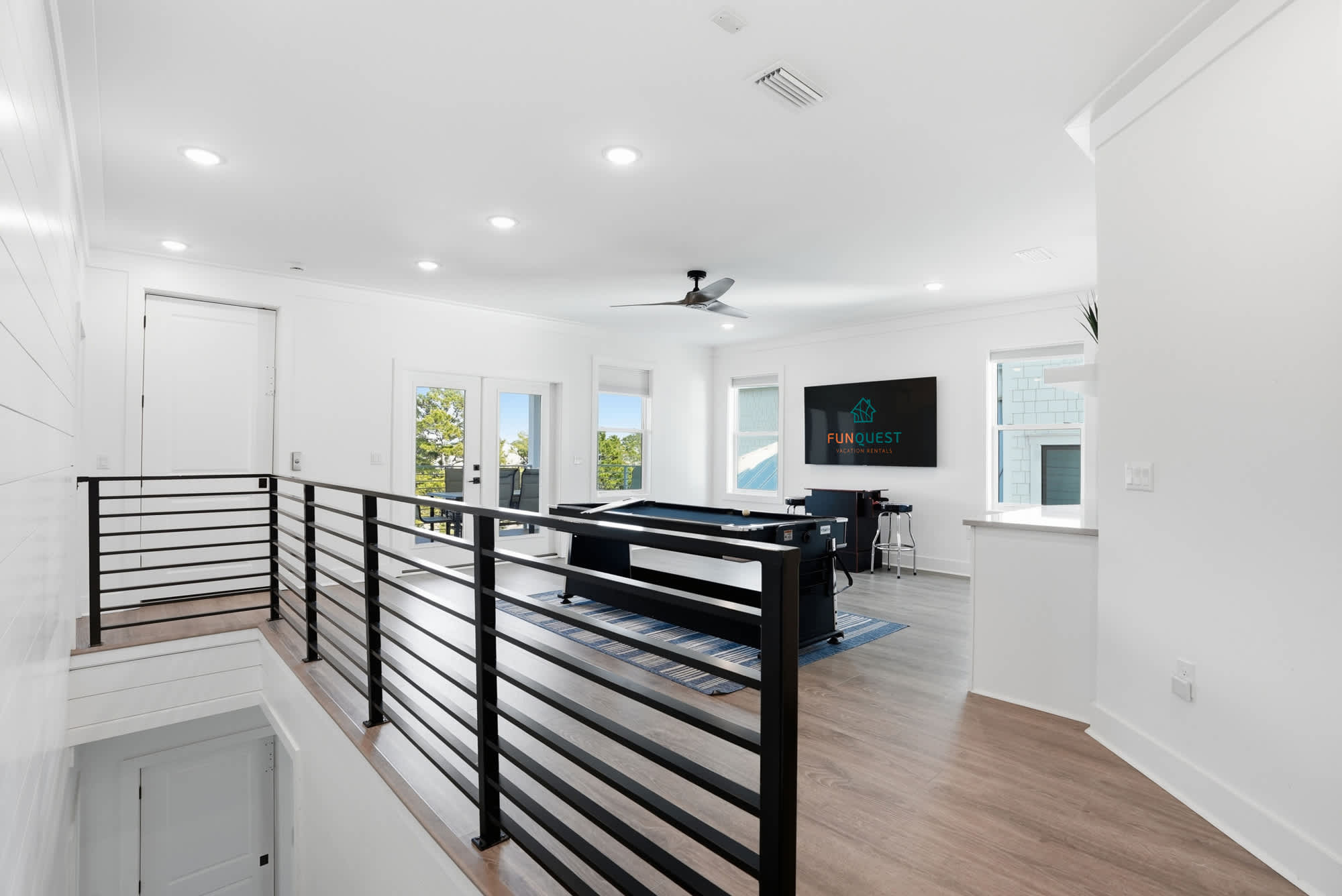 120 Dune Drive – Upper-level game room with pool table, large TV, and balcony access offering outdoor views.