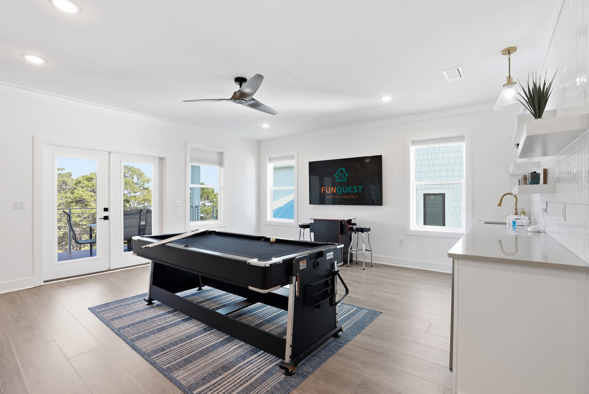 120 Dune Drive – Game room with pool table, TV, kitchenette, and balcony access overlooking trees.