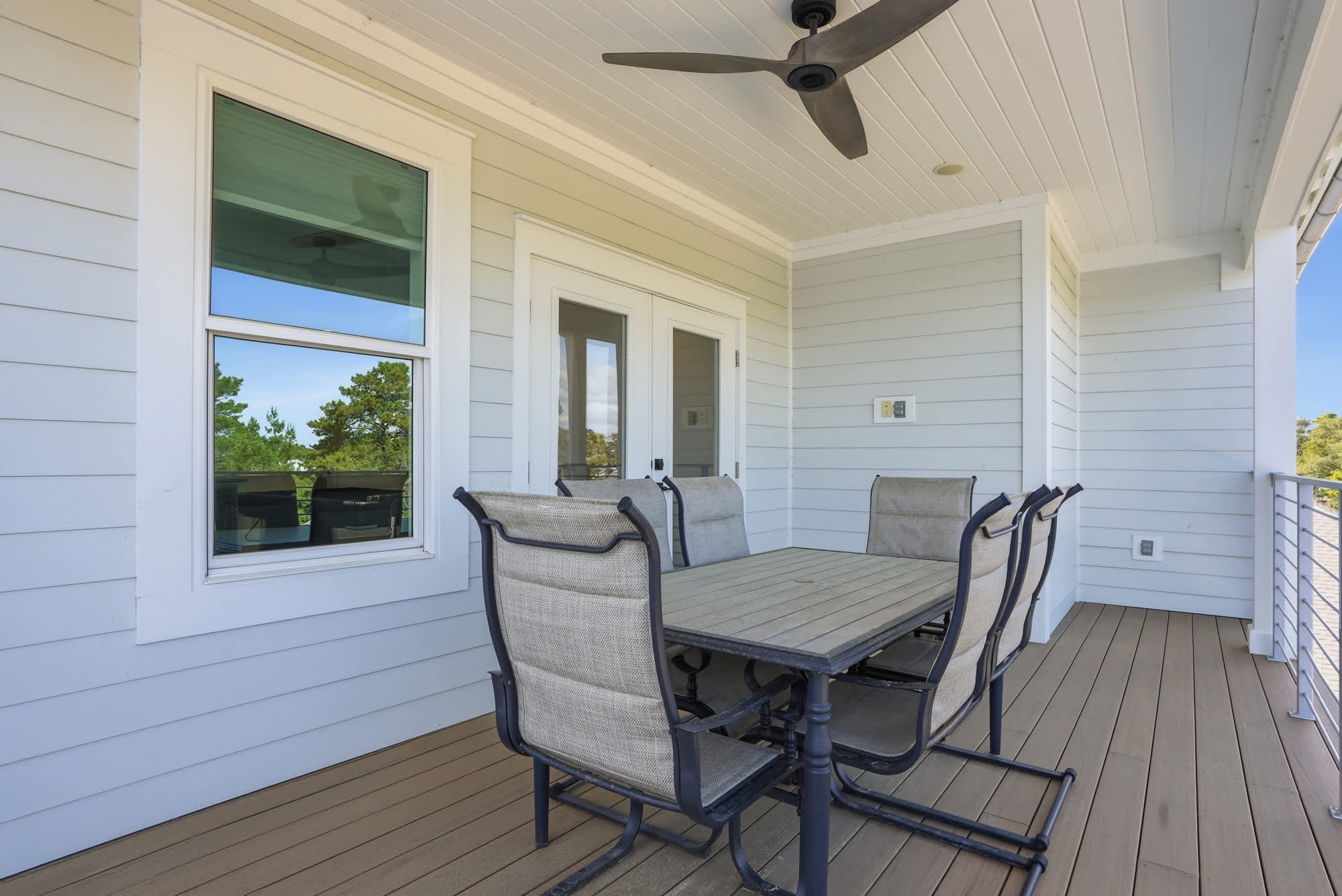 120 Dune Drive – Covered outdoor patio with a dining table, chairs, and view of trees.