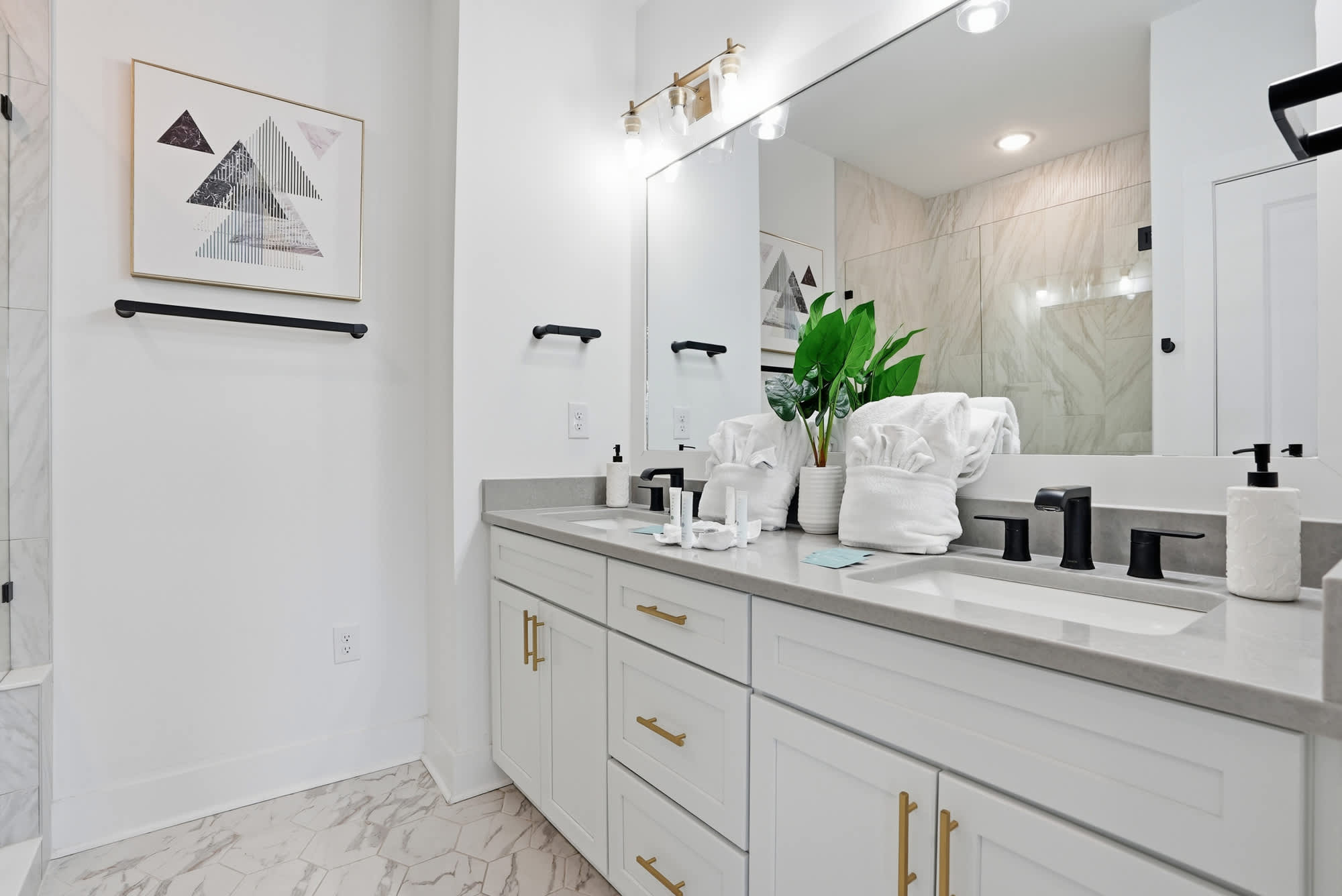 120 Dune Drive – Bright bathroom with double sinks, modern fixtures, and a large mirror, featuring a sleek design and decorative plant.