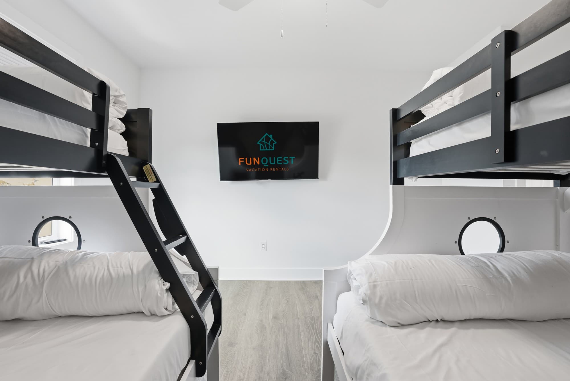 120 Dune Drive – Bunk room with black bunk beds, a television on the wall, and light-colored flooring.