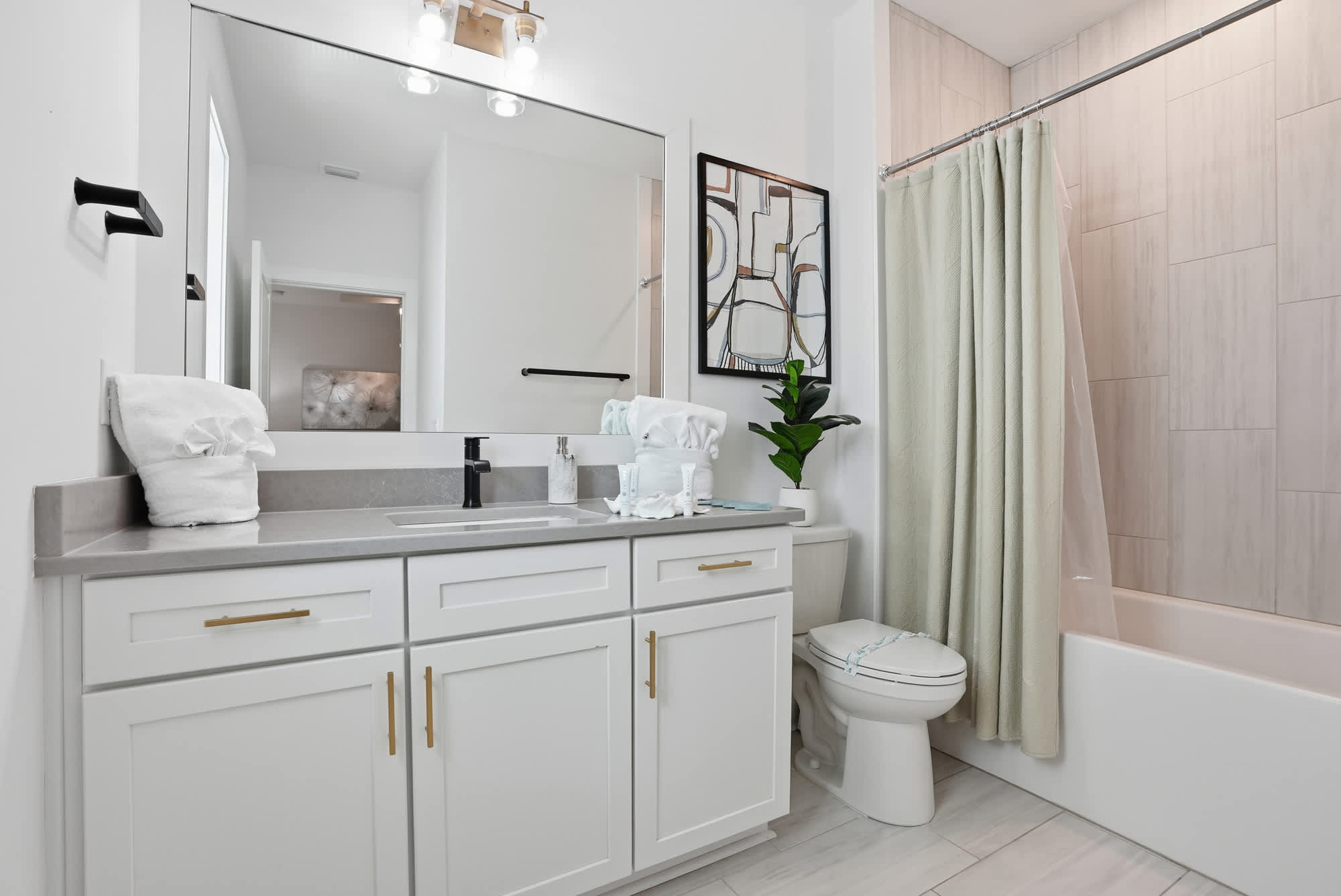 120 Dune Drive – Modern bathroom with a sink, large mirror, bathtub, and light ceramic tile.